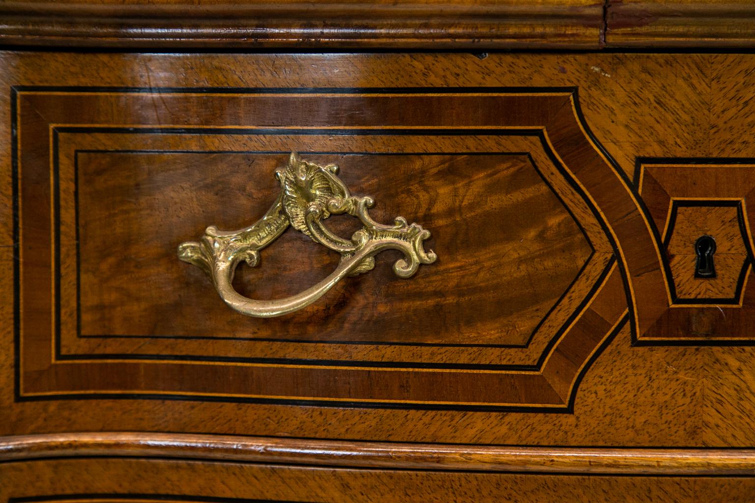 French inlaid serpentine two-drawer table having bookmatched burl walnut with inlaid satinwood and rosewood star. It has interlacing cross bandings made of ebony, boxwood, and fruitwood. It is serpentine on all four finished sides and has carved