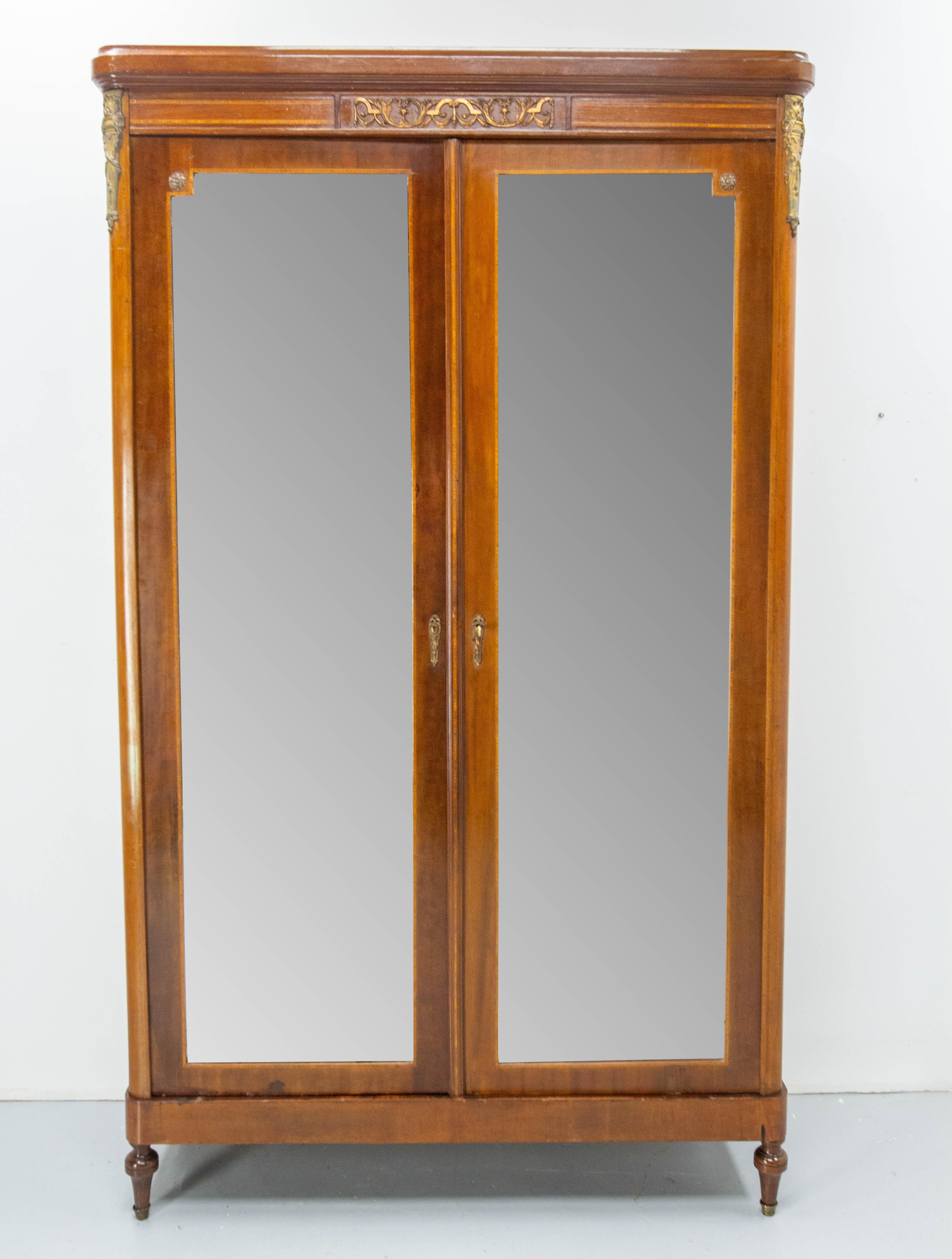 French Armoire with two beveled mirrors
Revival Louis 16 style iroko veneer and brass.
Finished interior with shelves and two little drawers.
Two doors with one kee.
Made circa 1900.
Good condition, with traces of the past 

Shipping:
4 packs
 