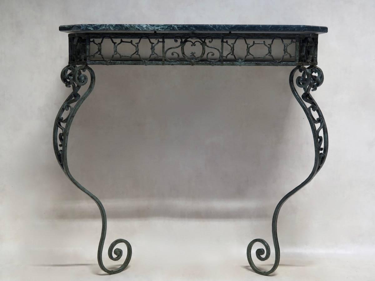 Very pretty and unusual console table, made of riveted wrought iron in an intricate pattern, with original Verdigris patina. The cabriole legs end in exaggeratedly scrolling feet. The elegant green marble top, veined with white, has canted corners.