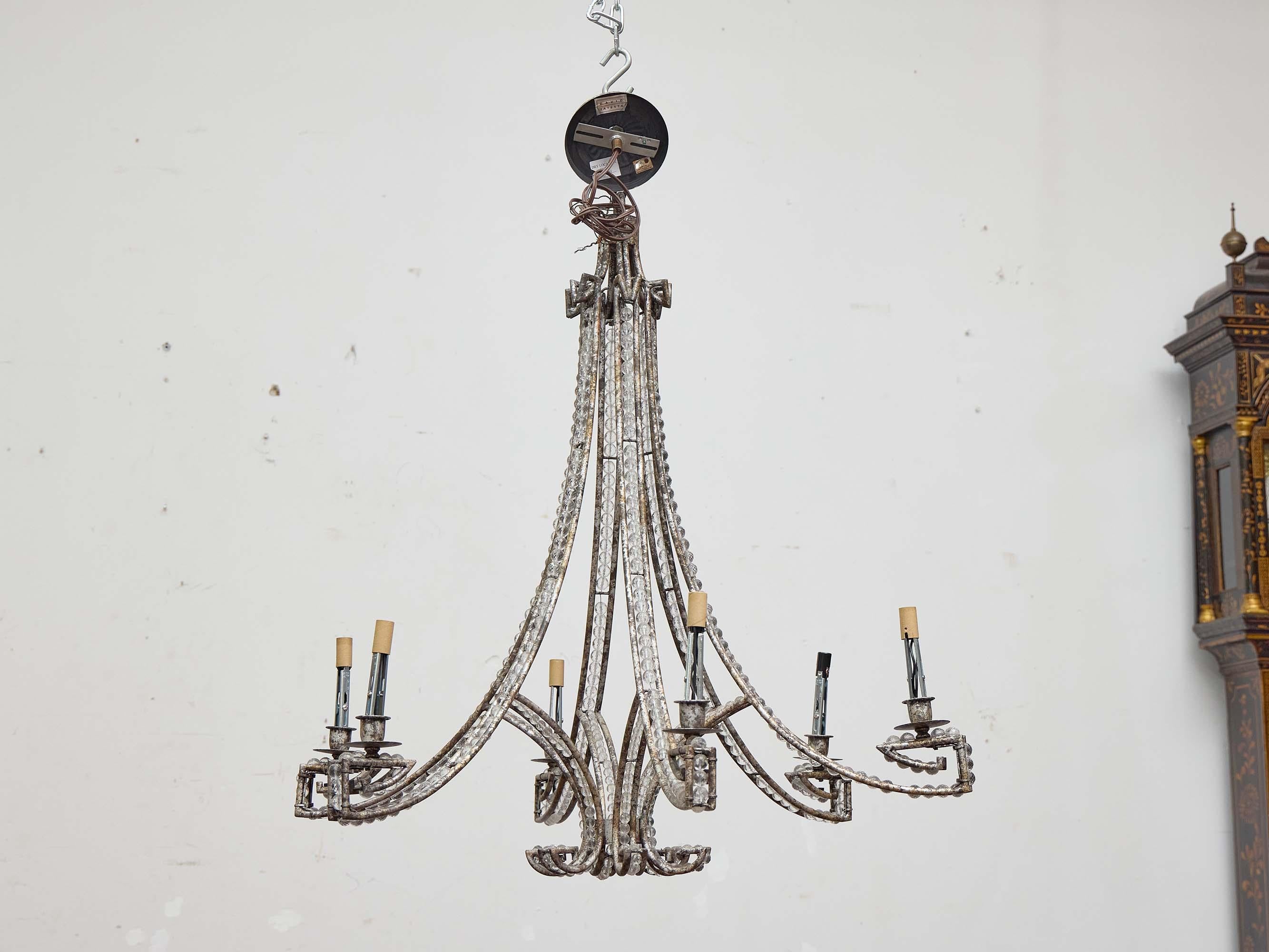 Ein französischer Kronleuchter aus dem 19. Jahrhundert aus handgeschmiedetem Eisen, reich verziert mit Strängen aus geschliffenen Glasperlen. Die Struktur des Kronleuchters wird durch seine anmutige, langgestreckte Silhouette bestimmt, die sich aus