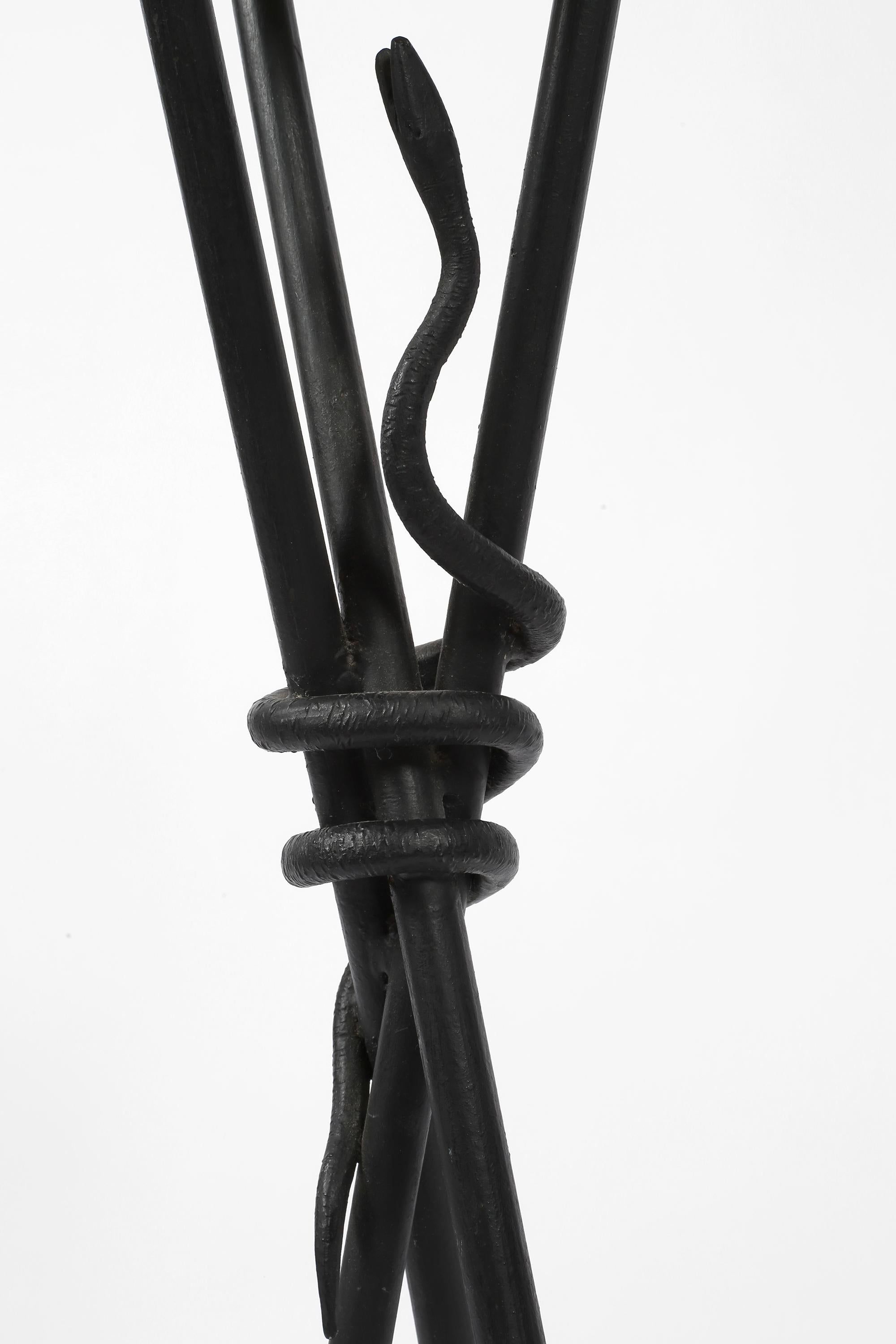 Table à boissons en fer émaillé noir et laiton, avec trois supports en forme de flèche stylisée et un serpent enroulé au centre.

Français, c. 1950.