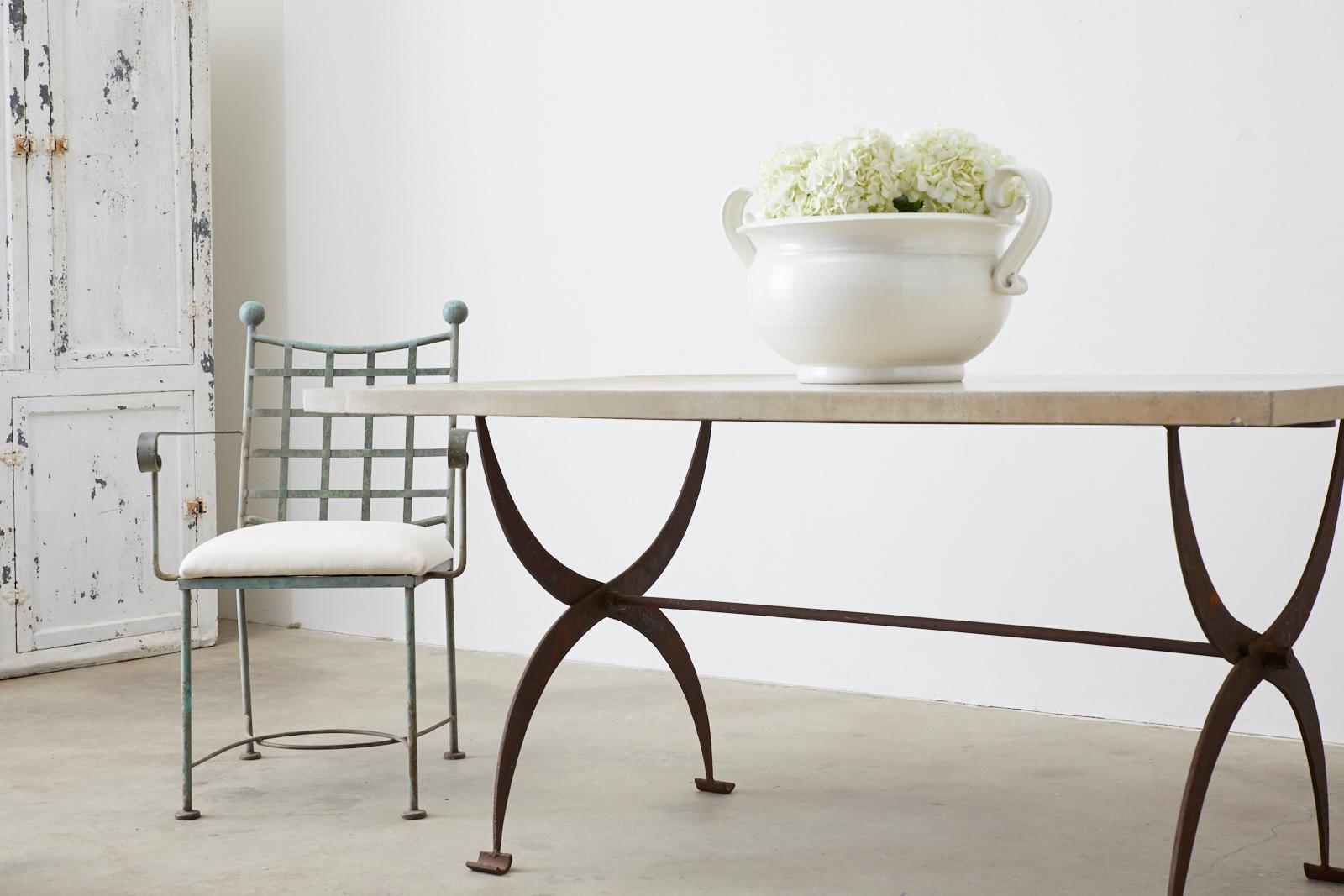 Industrial French pastry table originally having a marble top now features a 1.5 inch thick concrete top. The stone top has a fine polished finish with a rustic aged patina. The iron base has a scissor design leg construction ending with curved