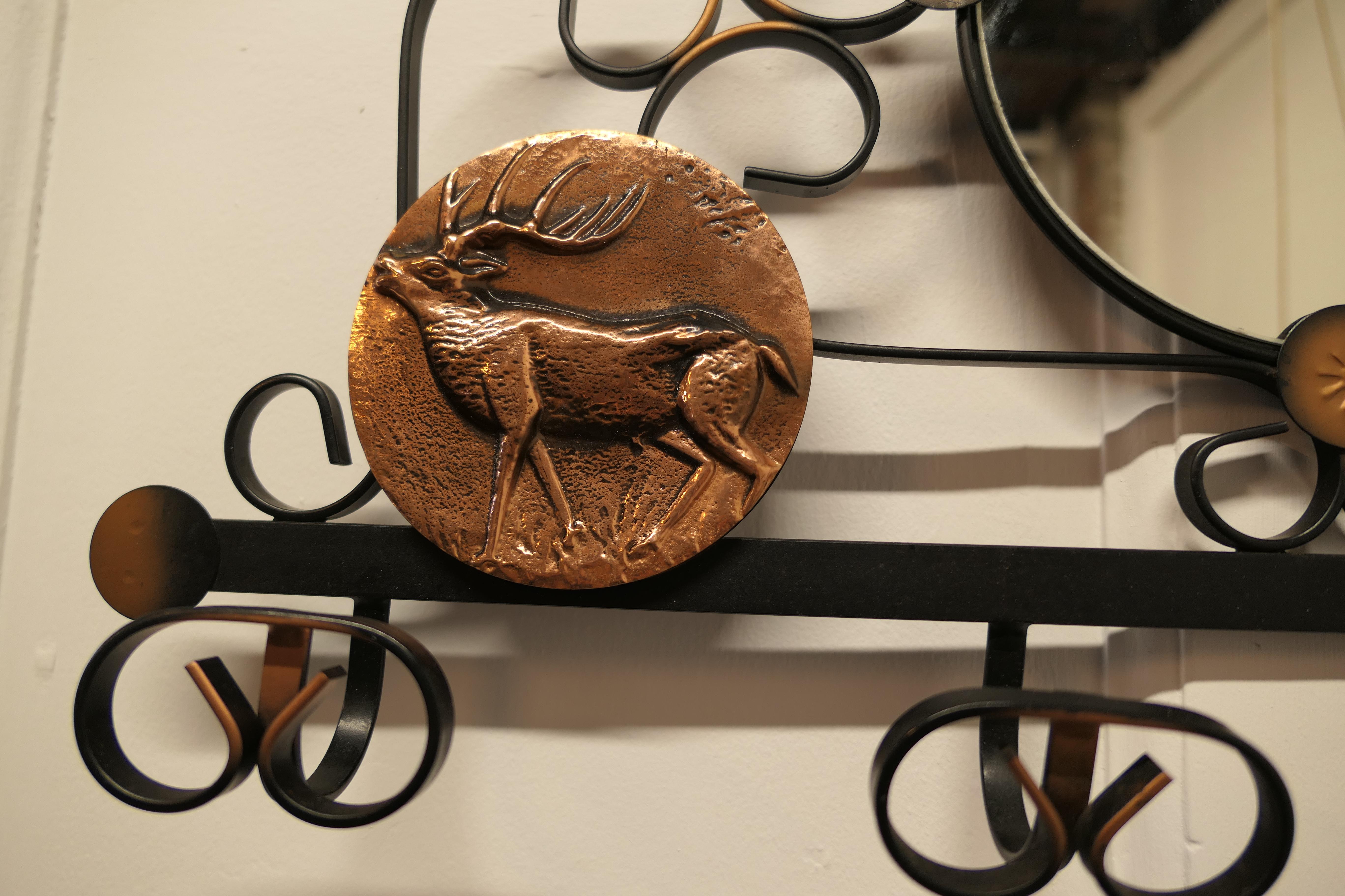French iron and copper hall coat hooks with mirror.

This is an attractive wall hanging mirror with 4 coat hooks beneath it has 3 decorative beaten copper panels on a Hunting theme with a stag on one and a huntsman taking aim on the other.
The