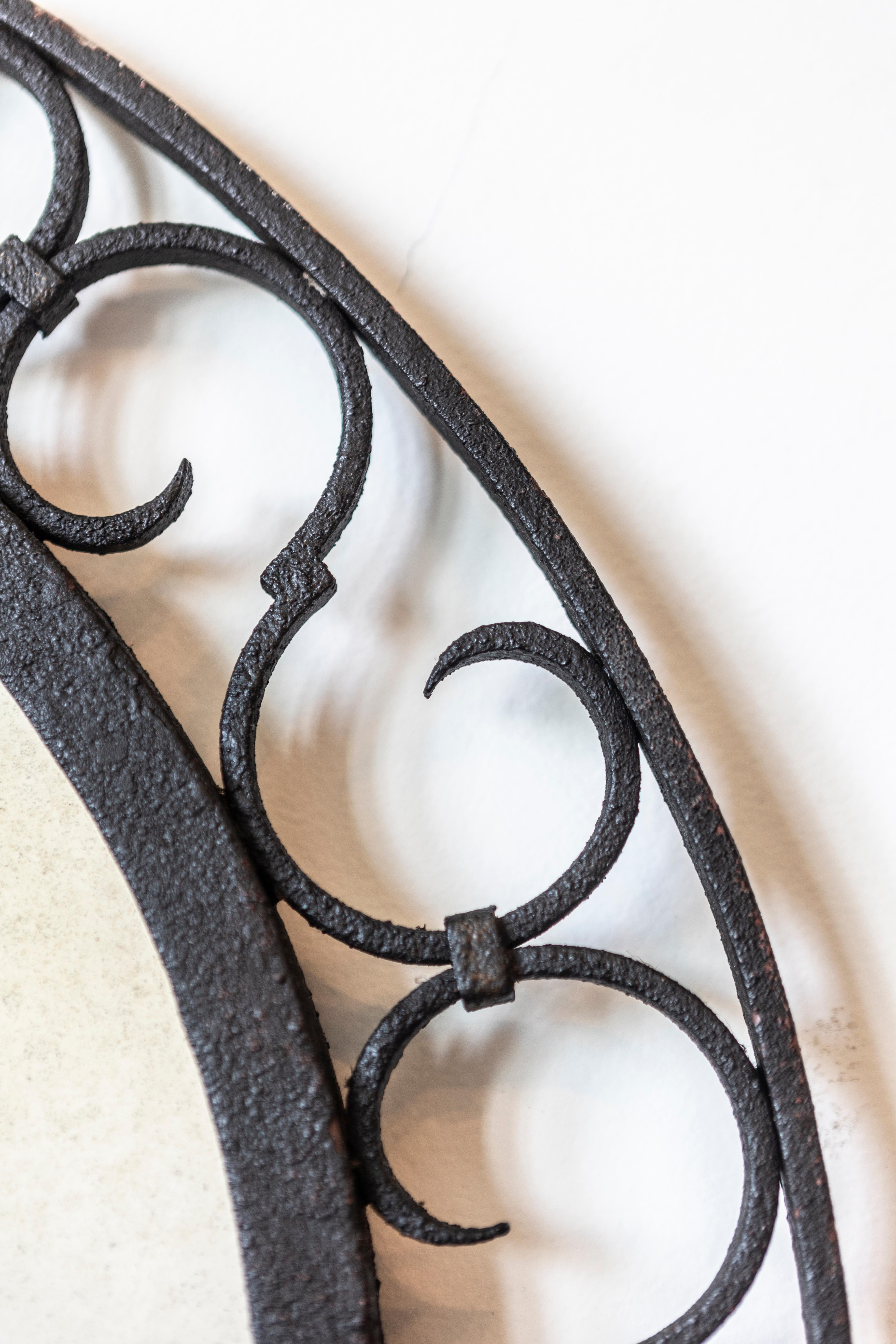 Français Miroir arqué en fer français avec motifs ajourés en forme de volute en S et crête de feuillage en vente