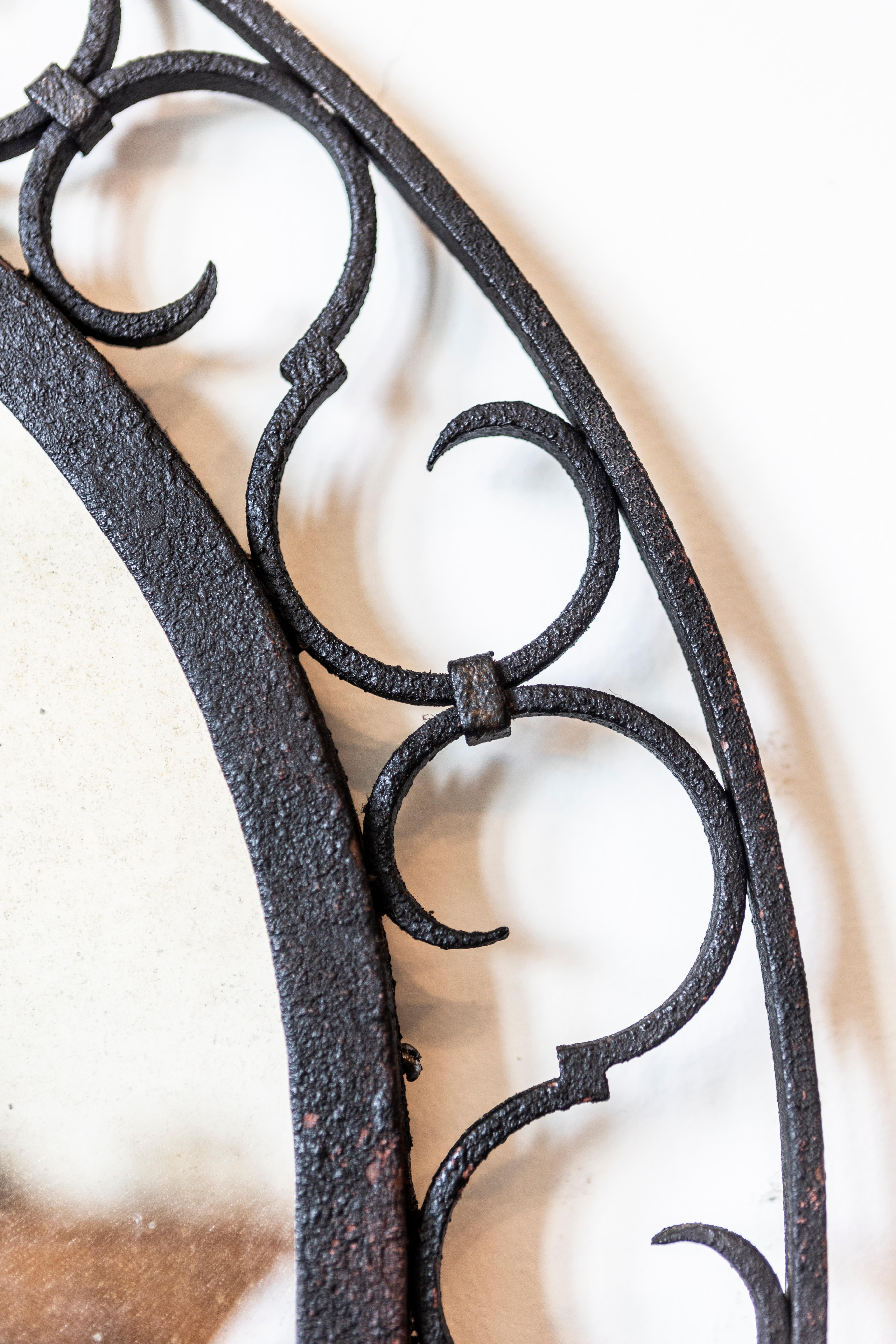 20ième siècle Miroir arqué en fer français avec motifs ajourés en forme de volute en S et crête de feuillage en vente