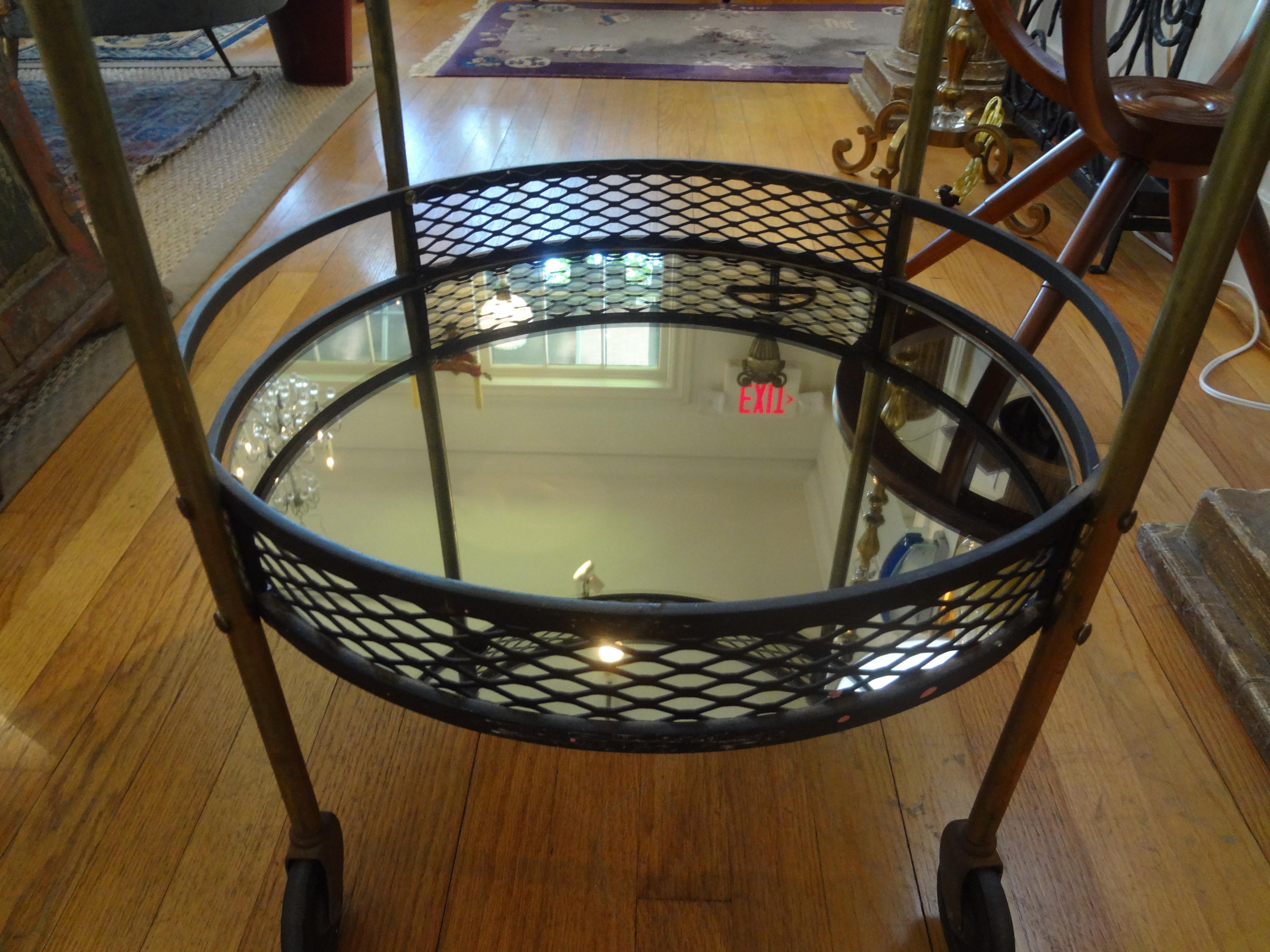 Interesting French iron and brass bar cart, drinks cart or drinks trolley attributed to Mathieu Matégot. This French Mid-Century Modernist round cart has a new glass top and mirrored bottom tier and dates to the 1960s. This versatile cart could be
