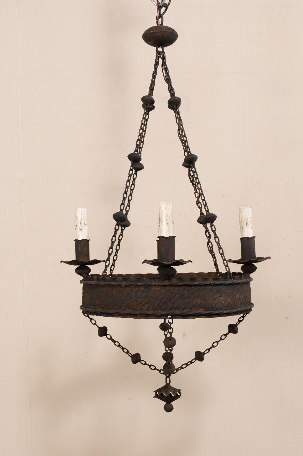 A French four-light iron ring chandelier from the mid-20th century. This vintage chandelier from France features a basket design with central hammered and nicely textured ring, adorn with ruffled edging and twisted iron accents. Four ruffled iron
