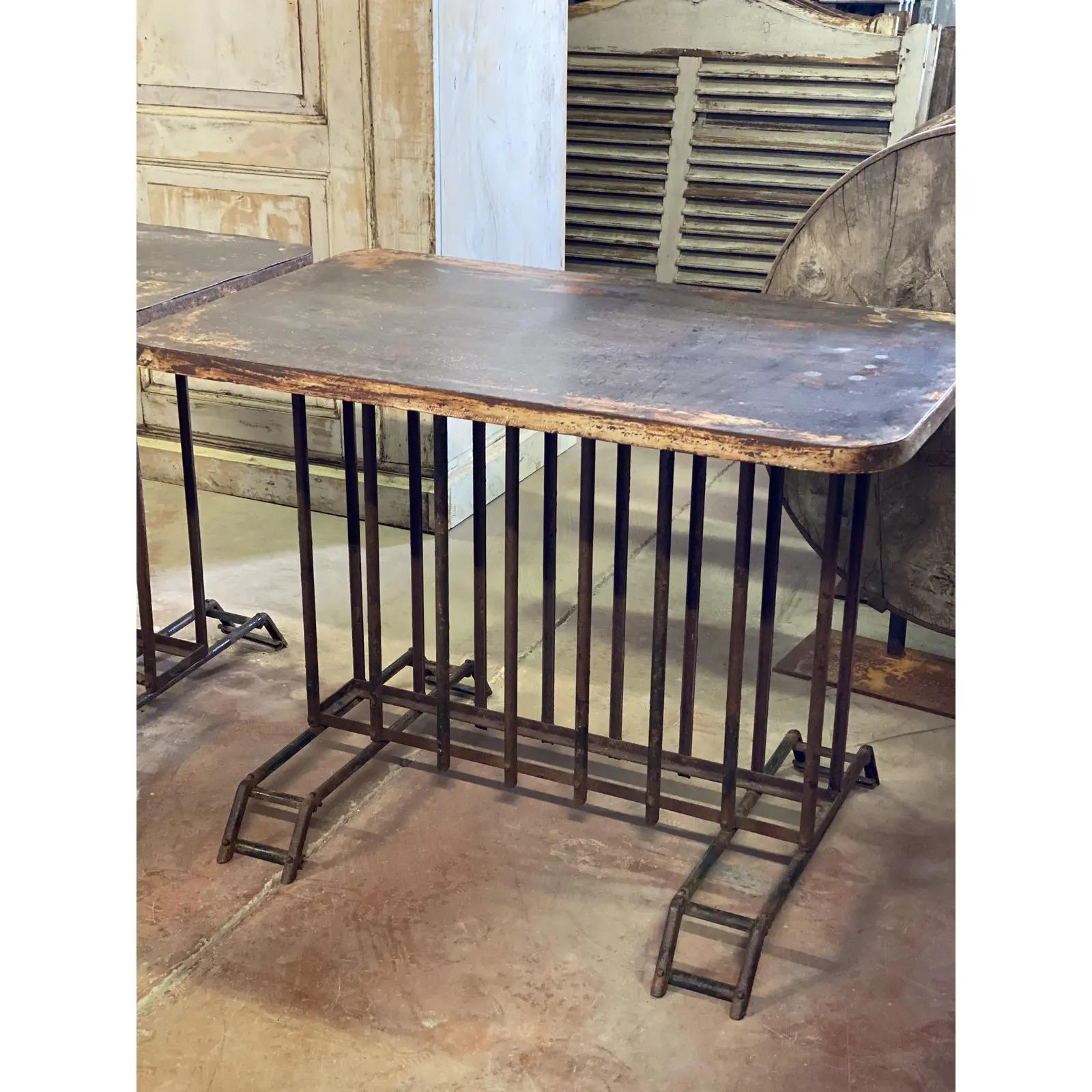 20th century French wrought iron bistro table with a layer painted finish. Interesting rusty patina. Very interesting rare design of the base. Very sturdy. Pair is available if desired.