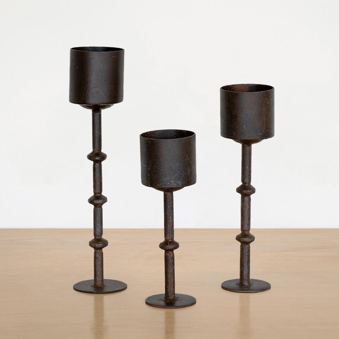 Great set of three vintage iron candle holders from France. Thin black iron stems hold iron cups, perfect for a pillar candle. Vintage iron shows great age and patina. Staggering heights make for a beautiful display. 
Candle 1: 9