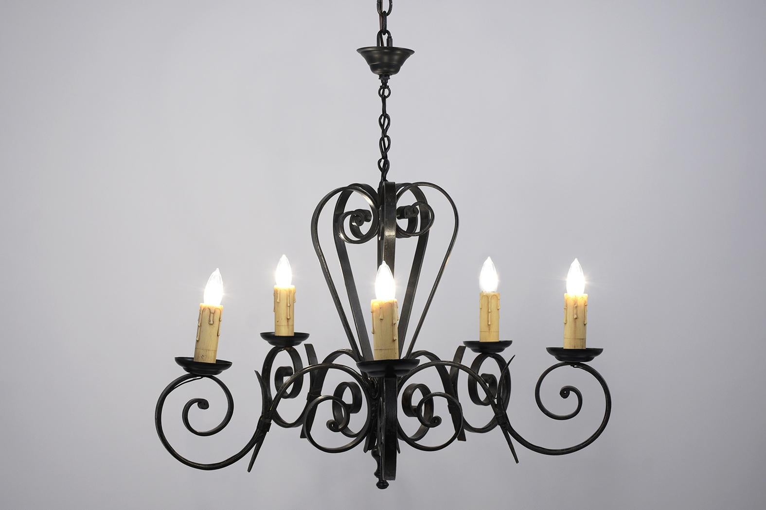 This French chandelier has been restored and is made out of iron. The chandelier features handcrafted scroll arms design, six lights painted in black color, newly waxed, and polished with a beautiful patina finish. This chandelier is wired to US