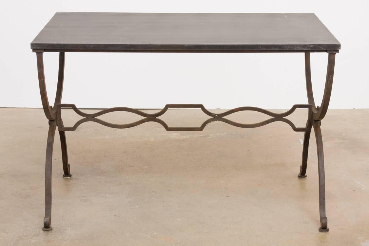 Élégante table basse ou de cocktail en fer forgé français dans le style et la manière de la Maison Jansen. Avec une base de style curule en forme de X, construite en fer massif épais. Rosettes décoratives sur les côtés et pieds incurvés se terminant