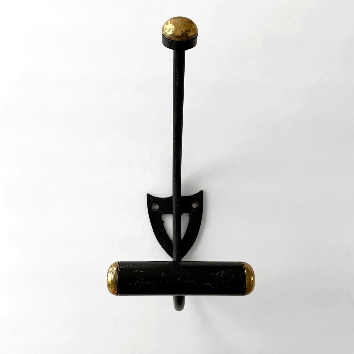 French iron double wall hooks
France, mid century
Beautifully contrasted iron with brass accents creates a palette to please    
Angled iron upper arm is finished with a rounded brass toned cap
Lower arm supports a rounded bar hook for wider storage