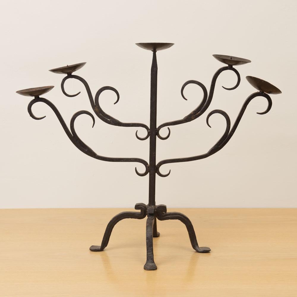 Impresionante candelabro vintage grande de hierro de cinco brazos procedente de Francia. Delgados brazos curvados con bellos detalles de volutas sobre una base de hierro de cuatro patas. El acabado original muestra una pátina y un envejecimiento