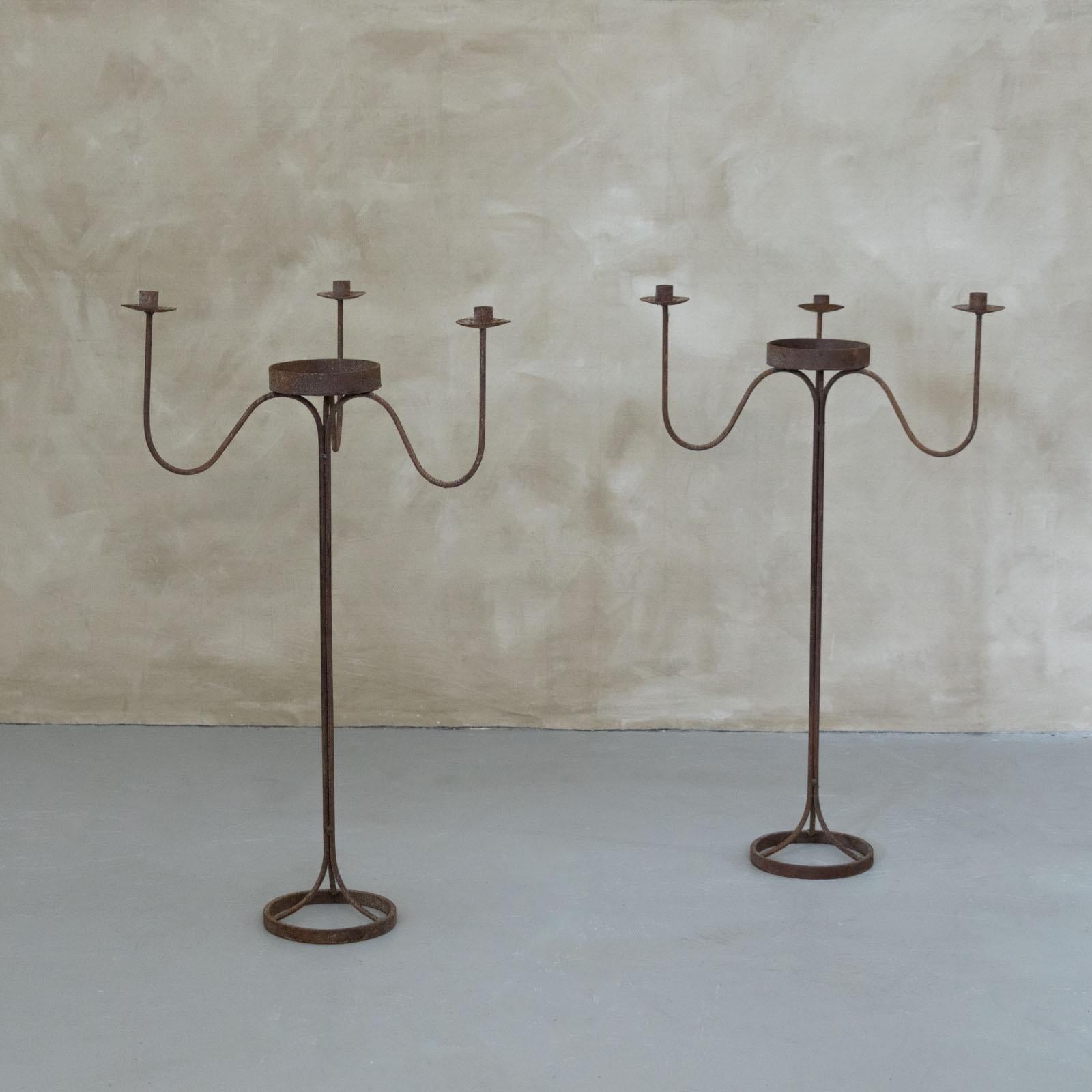Candelabro de pie único de hierro forjado procedente de Francia, años 40. Tres brazos ondulados se asientan sobre un tallo esbelto y una base circular de hierro forjado. Un bello complemento para cualquier habitación. Dos disponibles, se venden por