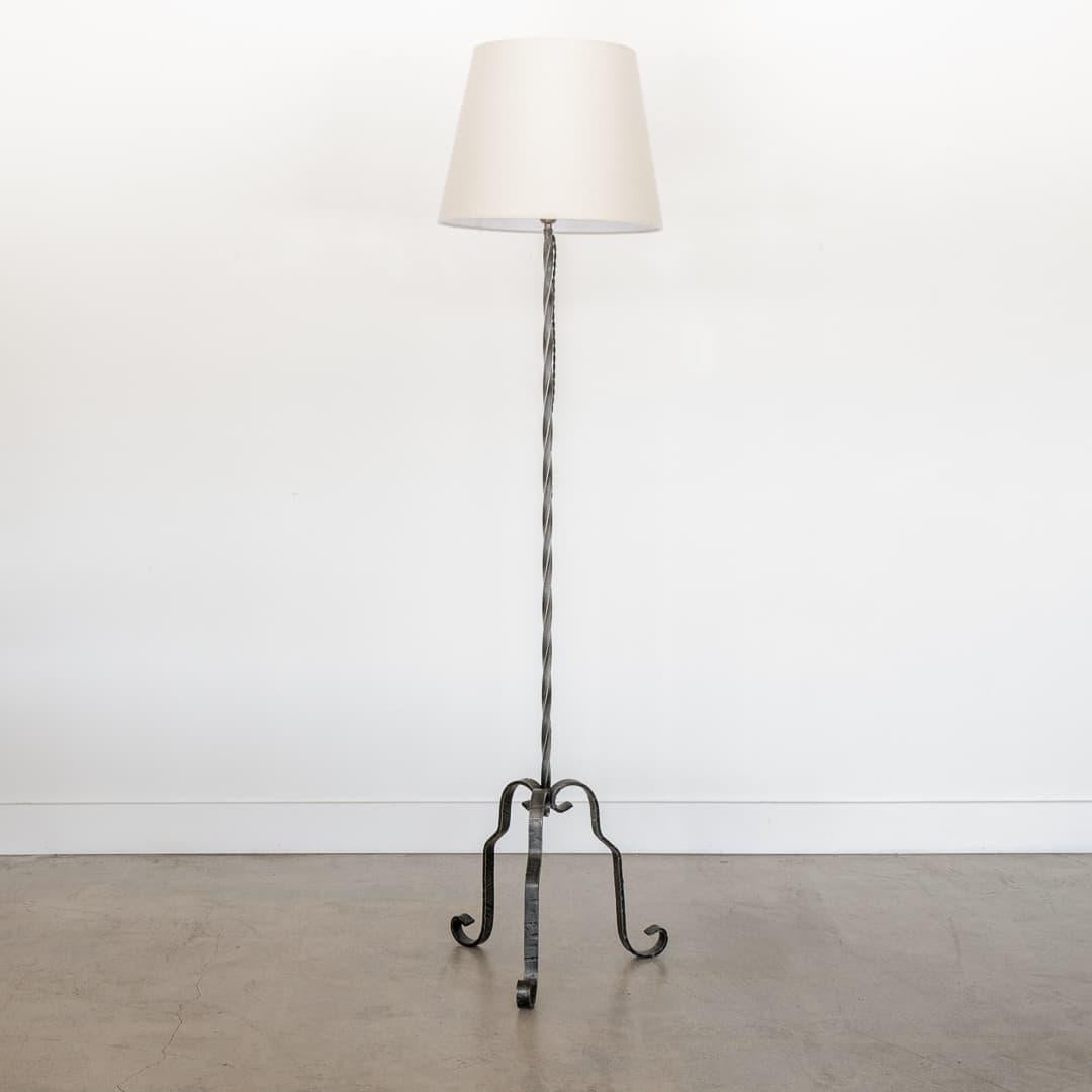 Incredible vintage wrought iron floor lamp from France, 1940s. Twisted iron stem with three wavy hammered iron legs and beautiful scroll detail on feet. New linen tapered shade and newly re-wired. Unique and striking piece. Takes one E26 base bulb,