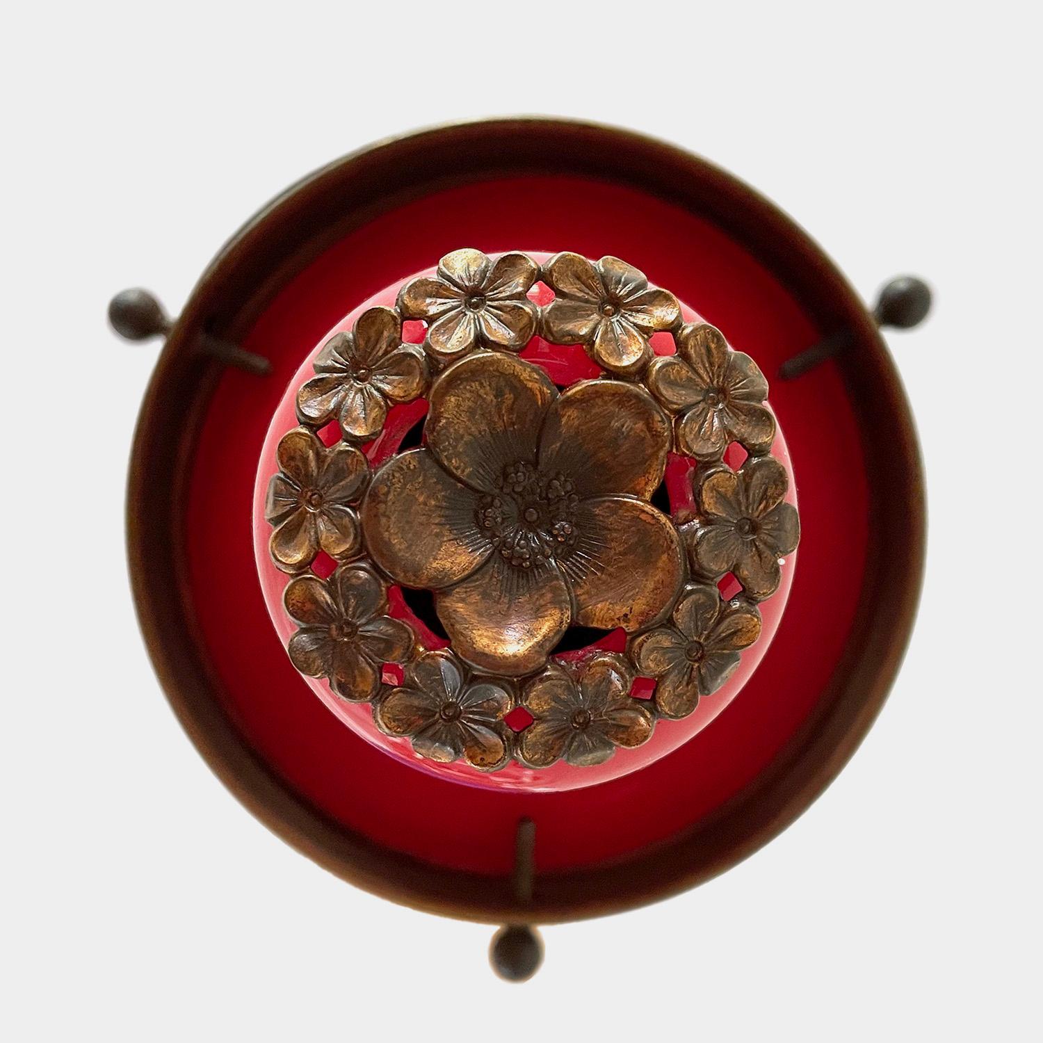 French iron & glass pendant light.
France, circa 1940s
Cathedral dome frame is suspended by a single hook
Red porcelain-like shade is adorned with a brass florette sculpture
Newly rewired
Single socket medium base.

6.25