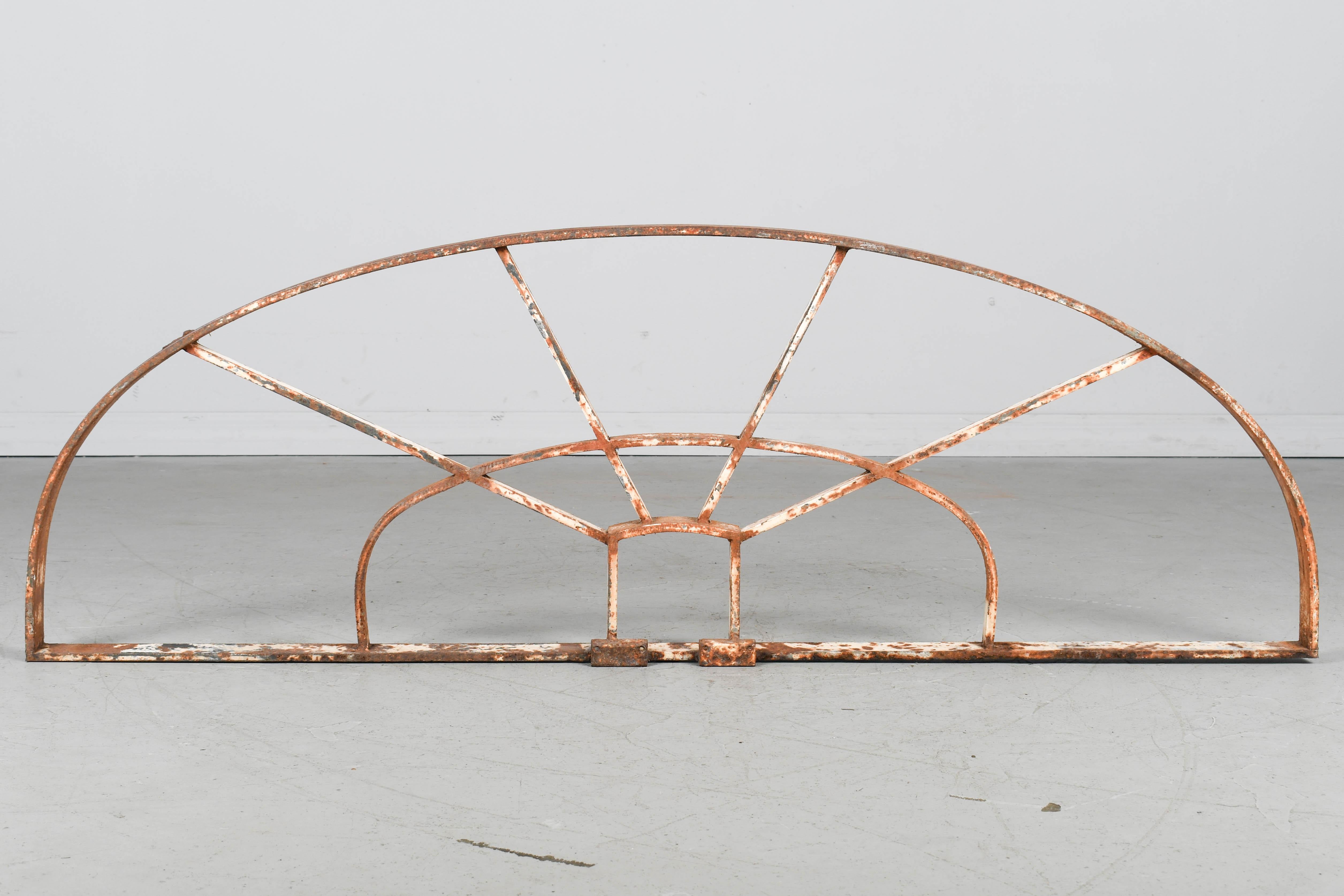 A salvaged French architectural arched iron grille or transom used to top a doorway or window. Rusty patina with remnants of white paint. Good quality iron work. Circa 1900-1910.
Dimensions: 57