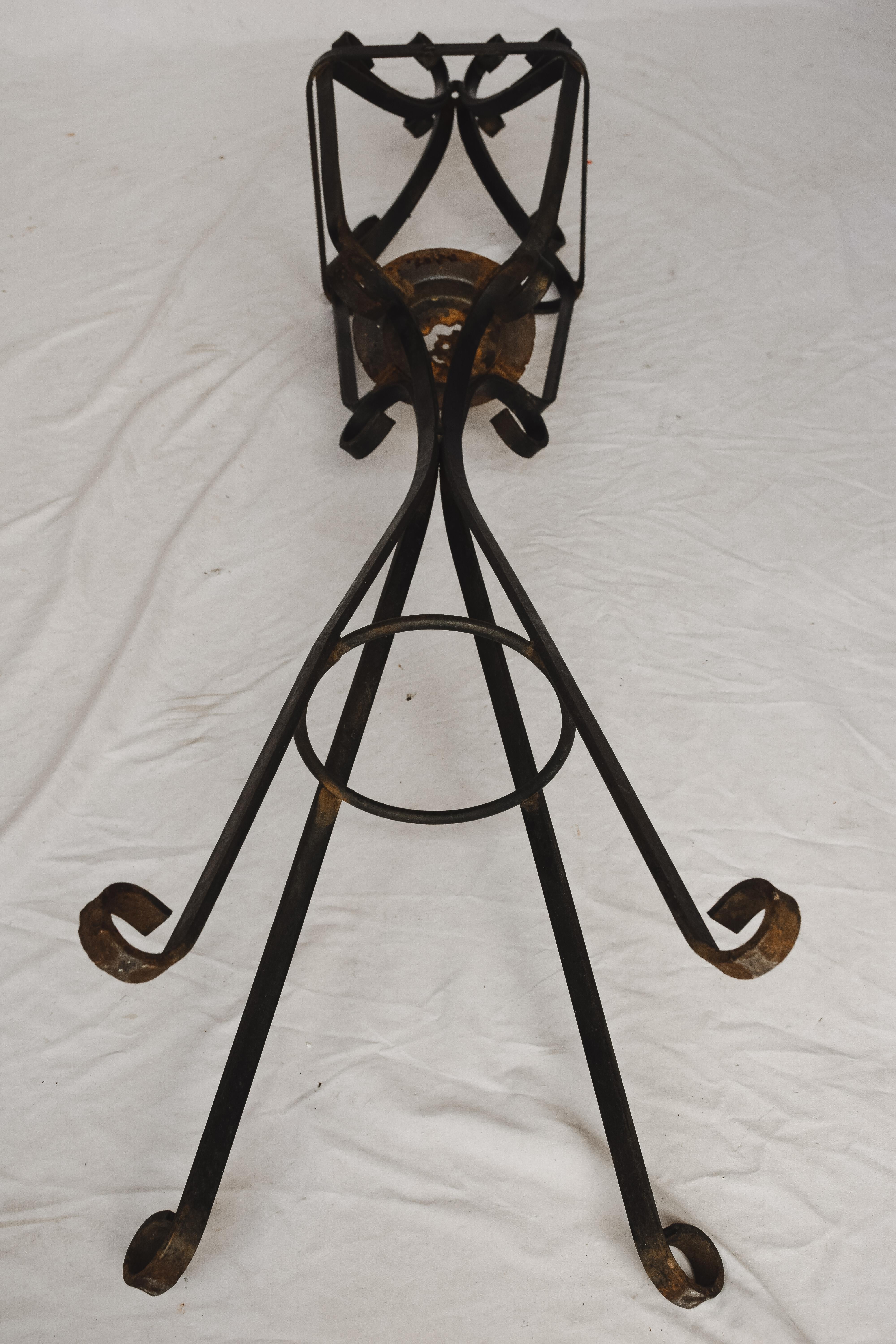 Forged in black iron this French Iron lantern stand would be perfect on a front porch as a holder for a plant or could house a candle to light up a cold autumn night. Accented with curled iron that looks like ribbon and a sturdy four legged