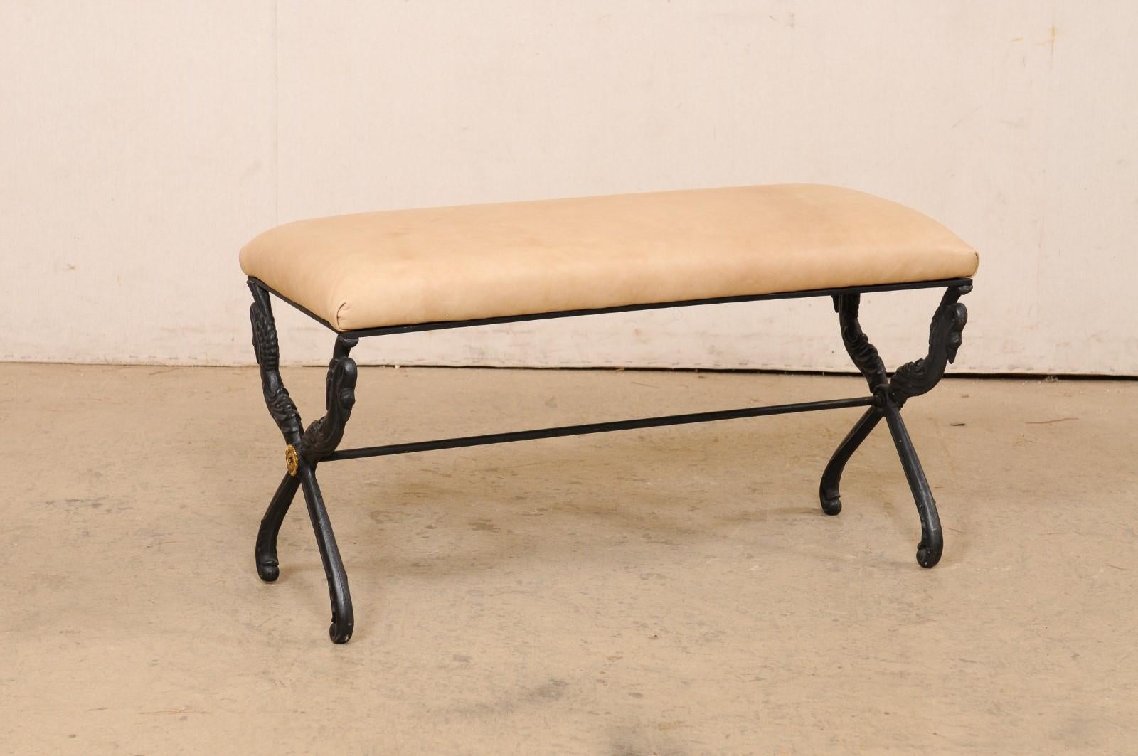 A French iron bench in swan motif with leather upholstered seat. This vintage bench from France has a rectangular-shaped seat which rests atop a black iron base that is risen by a pair of x-style legs at either side, and a slender stretcher bar