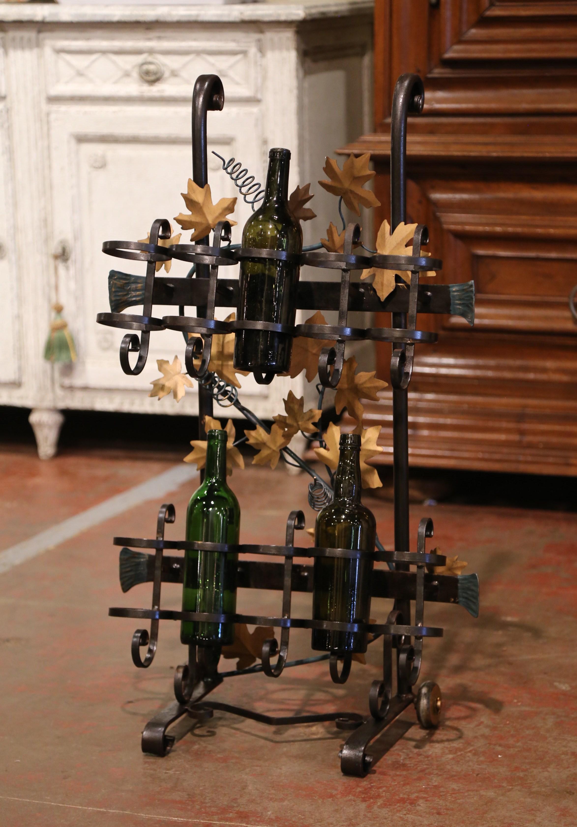 Crafted in the Rhone region of France circa 2000, the cart is forged of iron and decorated with gold painted metal vine leaves. The rack with front handles and back wheels for easy handling, features two rows of five bottle cups and will hold up to