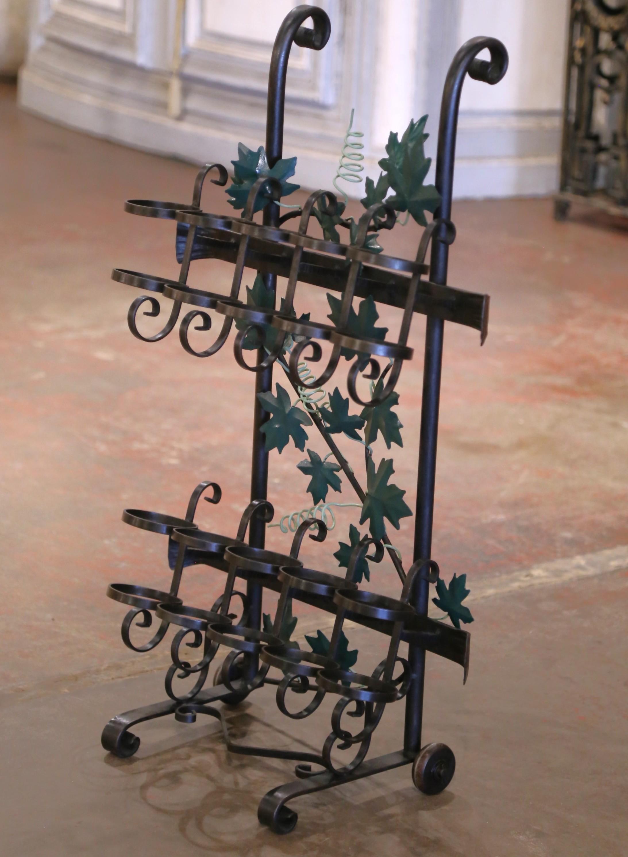 Crafted in the Rhone region of France circa 2000, the cart is forged of iron and decorated with green painted metal vine leaves. The rack with front handles and back wheels for easy handling, features two rows of five bottle cups and will hold up to