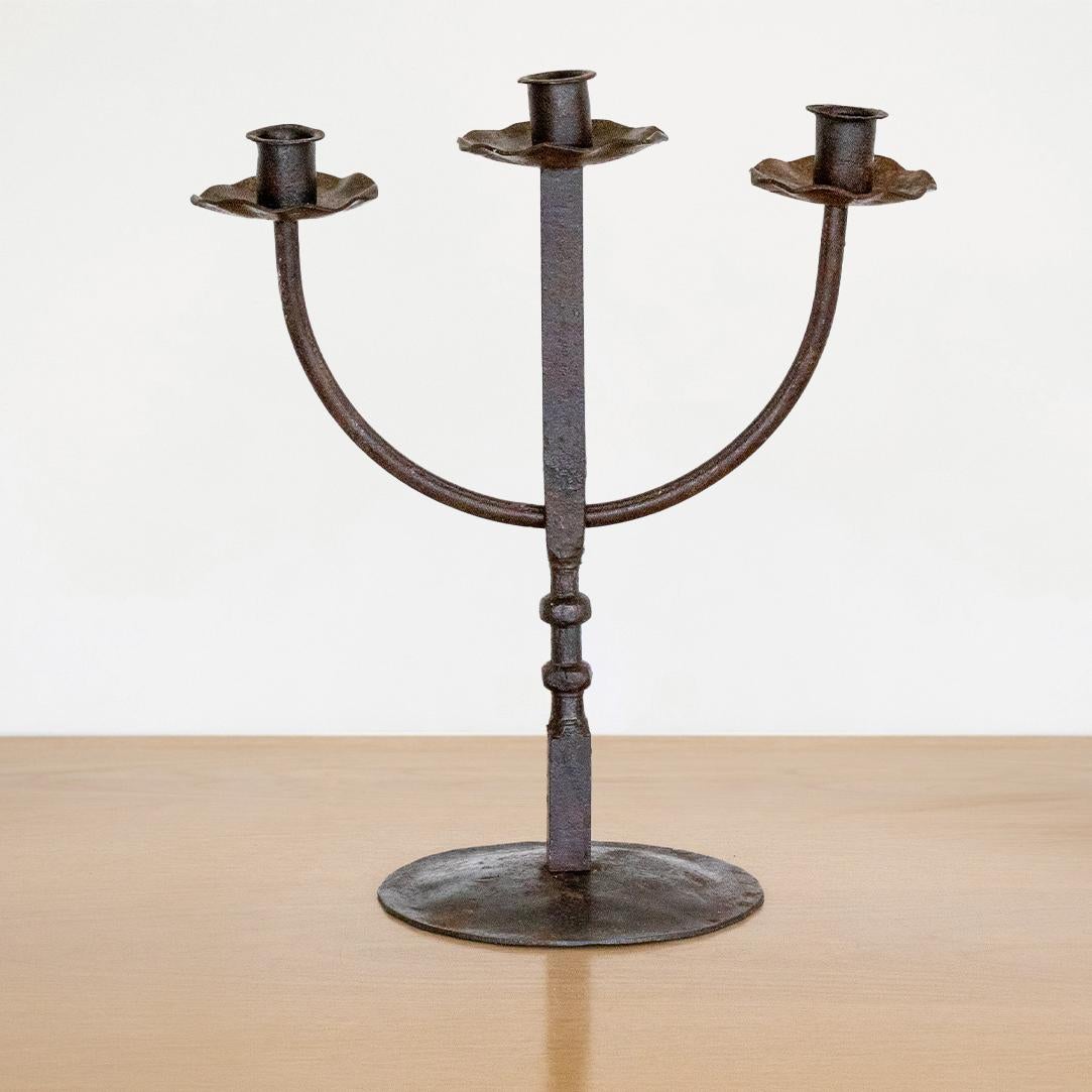 Vintage iron three arm candelabra from France. Curved arms with scalloped discs at each candleholder. Thin iron stem and circular base. Great age and patina to finish.