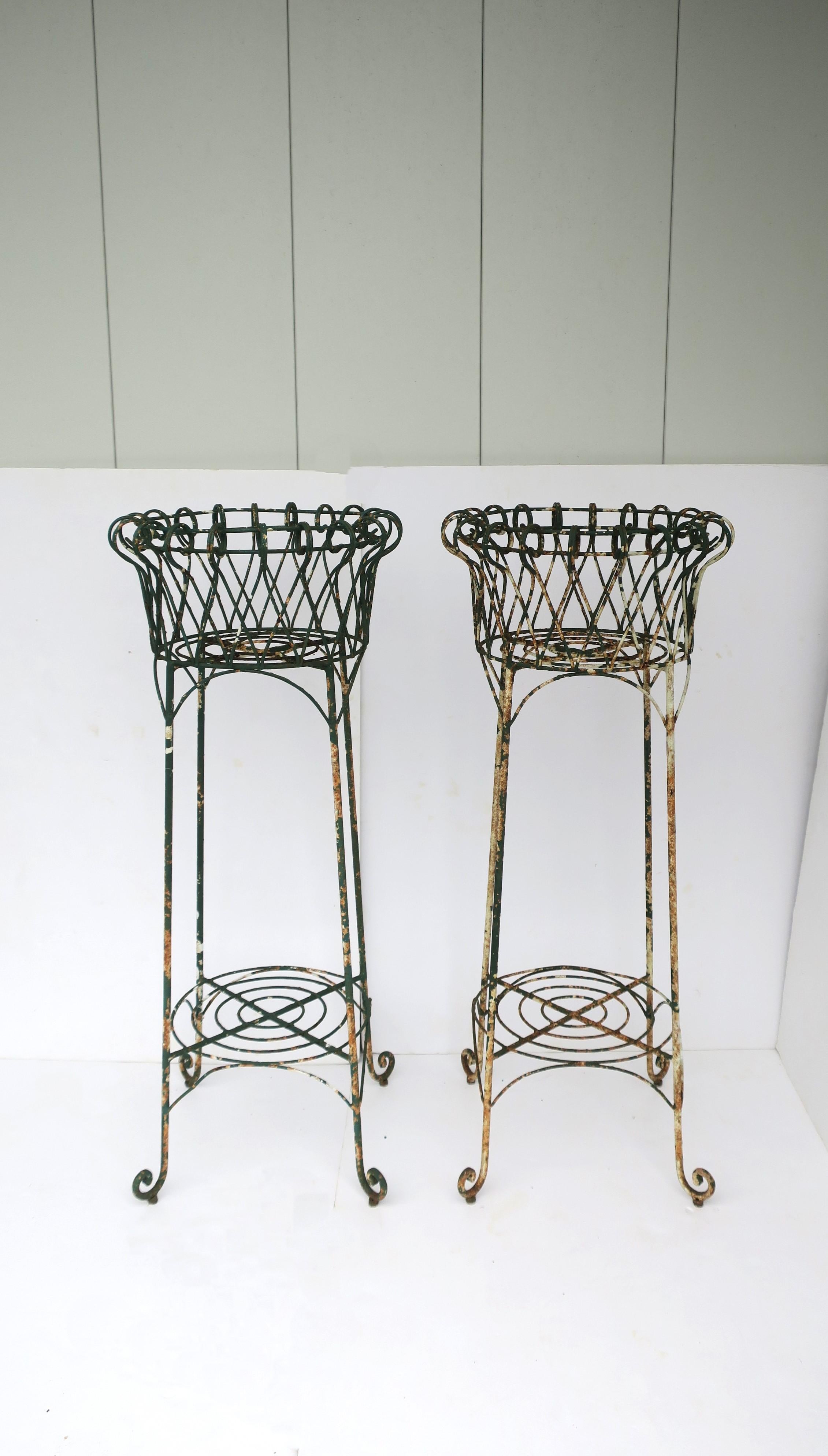 A pair of matching French iron wire garden plant pot holder stands jardinieres, circa early-20th century, France. This sculptural pair display beautifully as shown with ferns on outdoor porch area; set are green and white painted iron plant or
