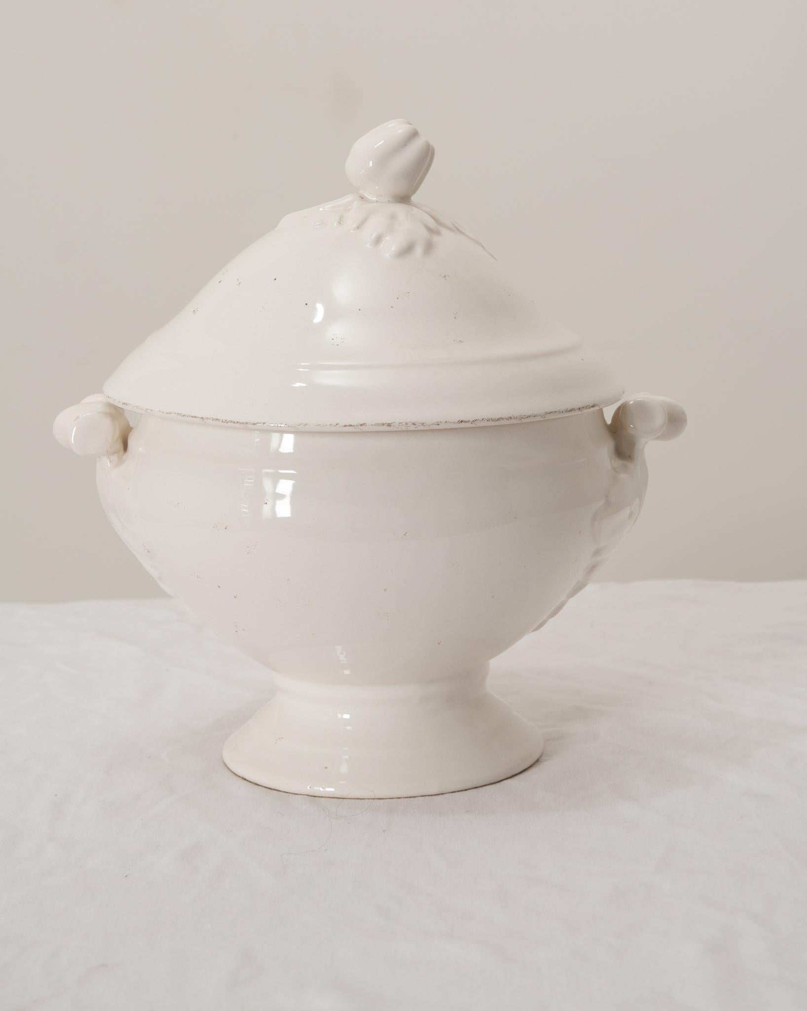A gorgeous antique French white ironstone lidded soup tureen with pedestal base, perfect for serving soups, stews, and gumbos.This fine soup tureen has a decorative bell pepper finial on the lid, lovely ornate handles, and an opaque creamy white