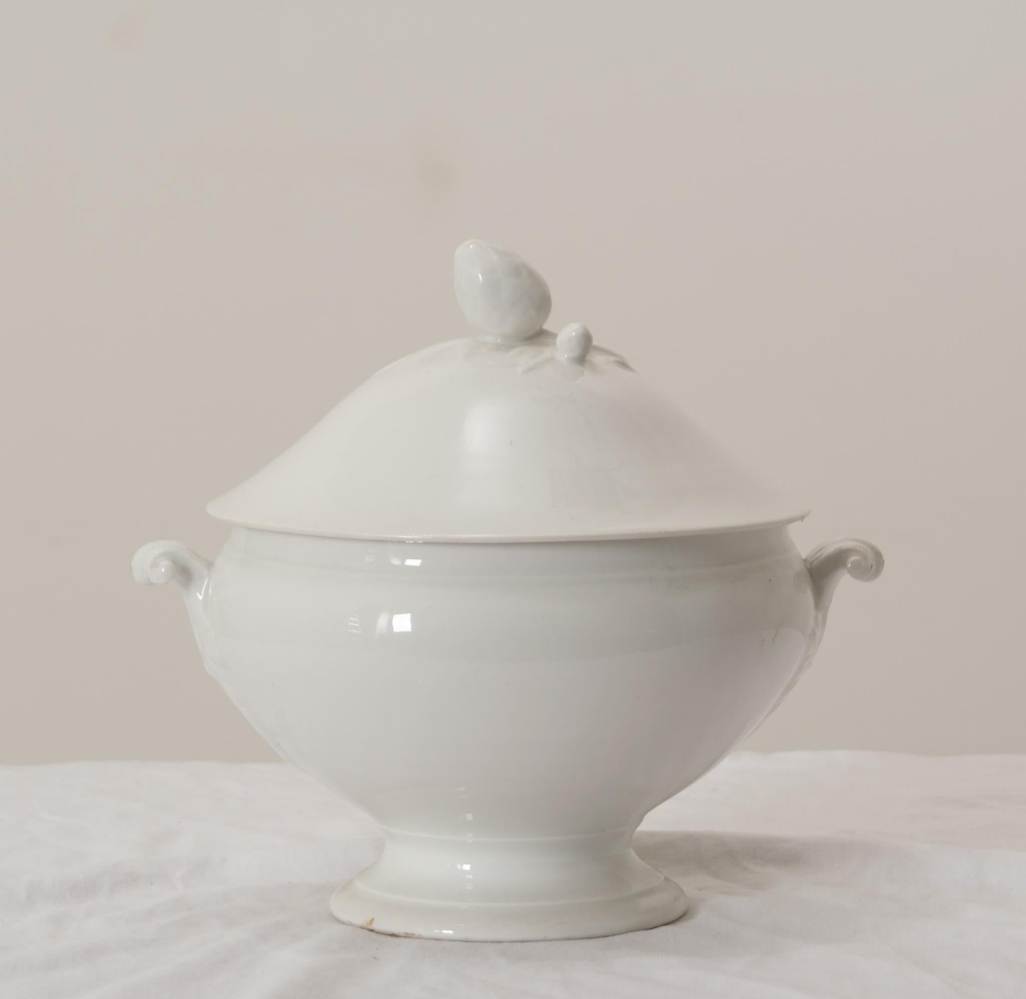 A gorgeous antique French white porcelain lidded soup tureen with pedestal base, perfect for serving soups, stews, and gumbos.This fine soup tureen has a decorative conical finial on the lid, lovely ornate scrolling handles, foliate motifs on the