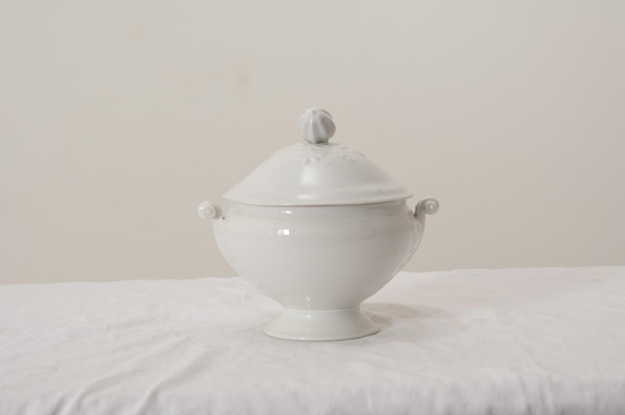 A gorgeous antique French white porcelain lidded soup tureen with pedestal base, perfect for serving soups, stews, and gumbos.This fine soup tureen has a decorative acorn squash finial on the lid, lovely ornate scrolling handles, foliate motifs on