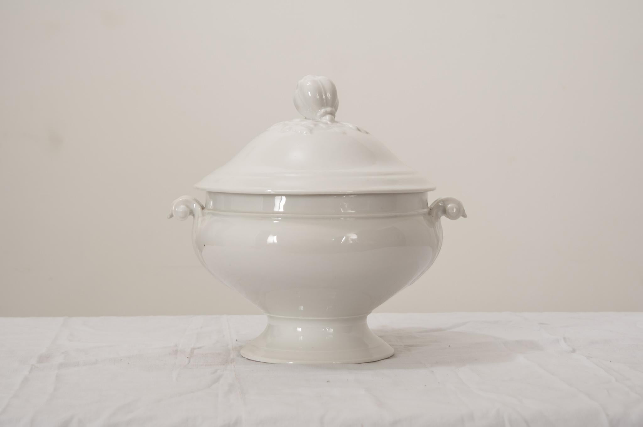A gorgeous antique French white ironstone lidded soup tureen with pedestal base, perfect for serving soups, stews, and gumbos.This fine tureen has a stylized pomegranate finial on the lid with decorative grape leaves, scrolling acanthus leaf handles