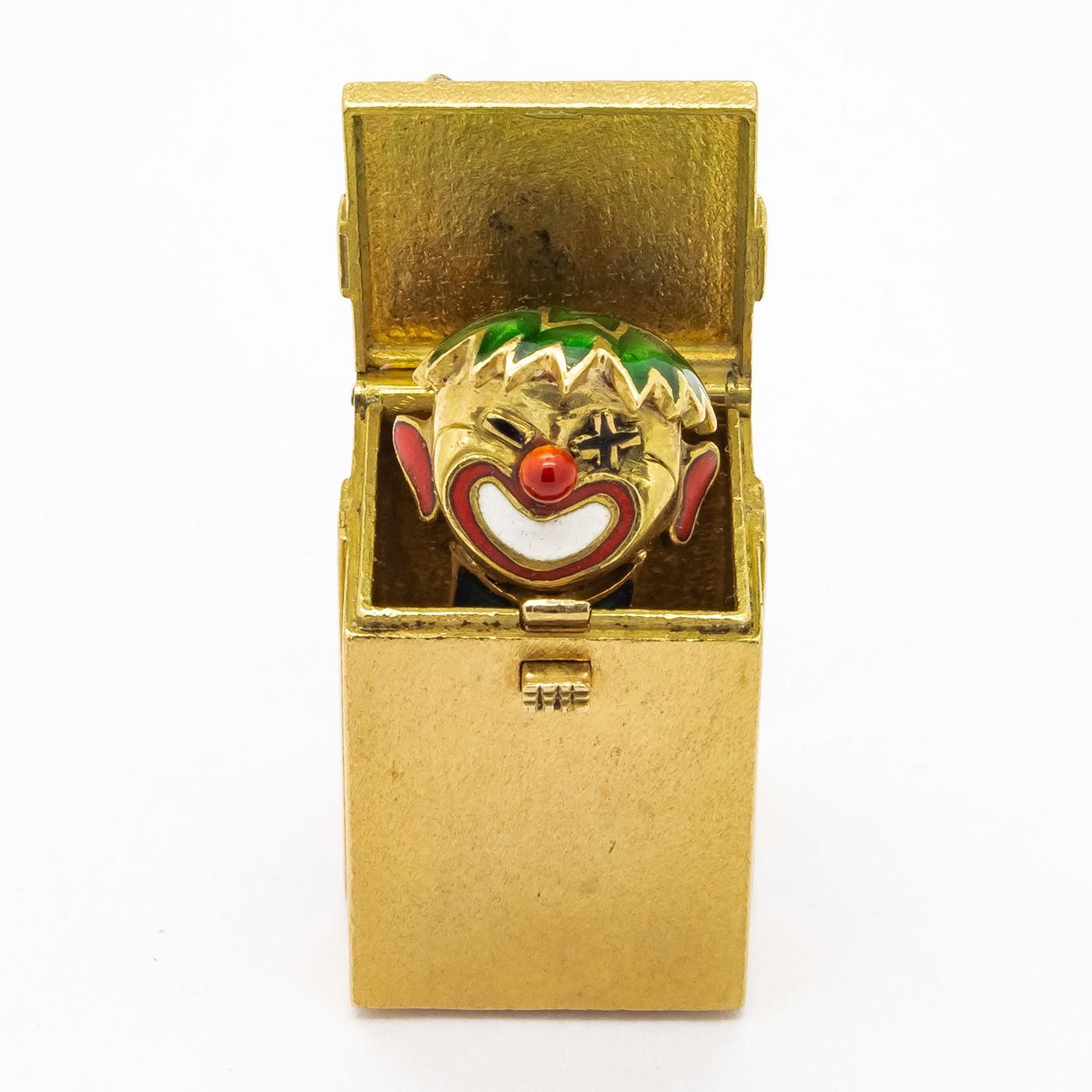 A French, gold and enamel, Jack-in-a-box pendant, mounted in 18ct gold, with a spring loaded Jack, partly enamelled in green, red and white enamel, in a surrounding box, tied with a blue enamelled ribbon, with two French eagle marks, for 18ct gold,