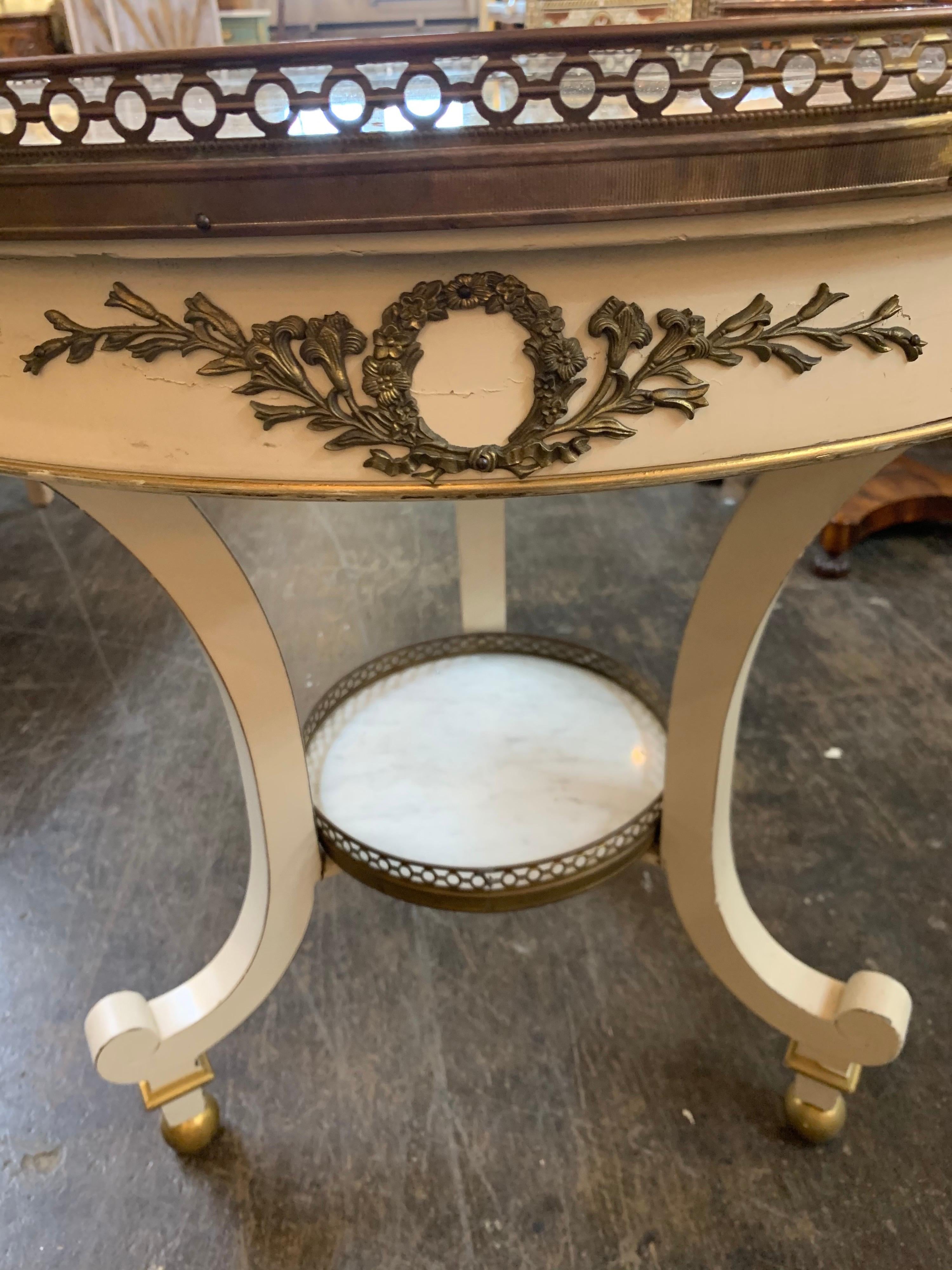 Lovely French Jansen style lacquered brass occasional table with foil mirror top. Nice decorative brass pieces along with curved legs. So pretty! Note there is a crack in the glass. Sold as is.