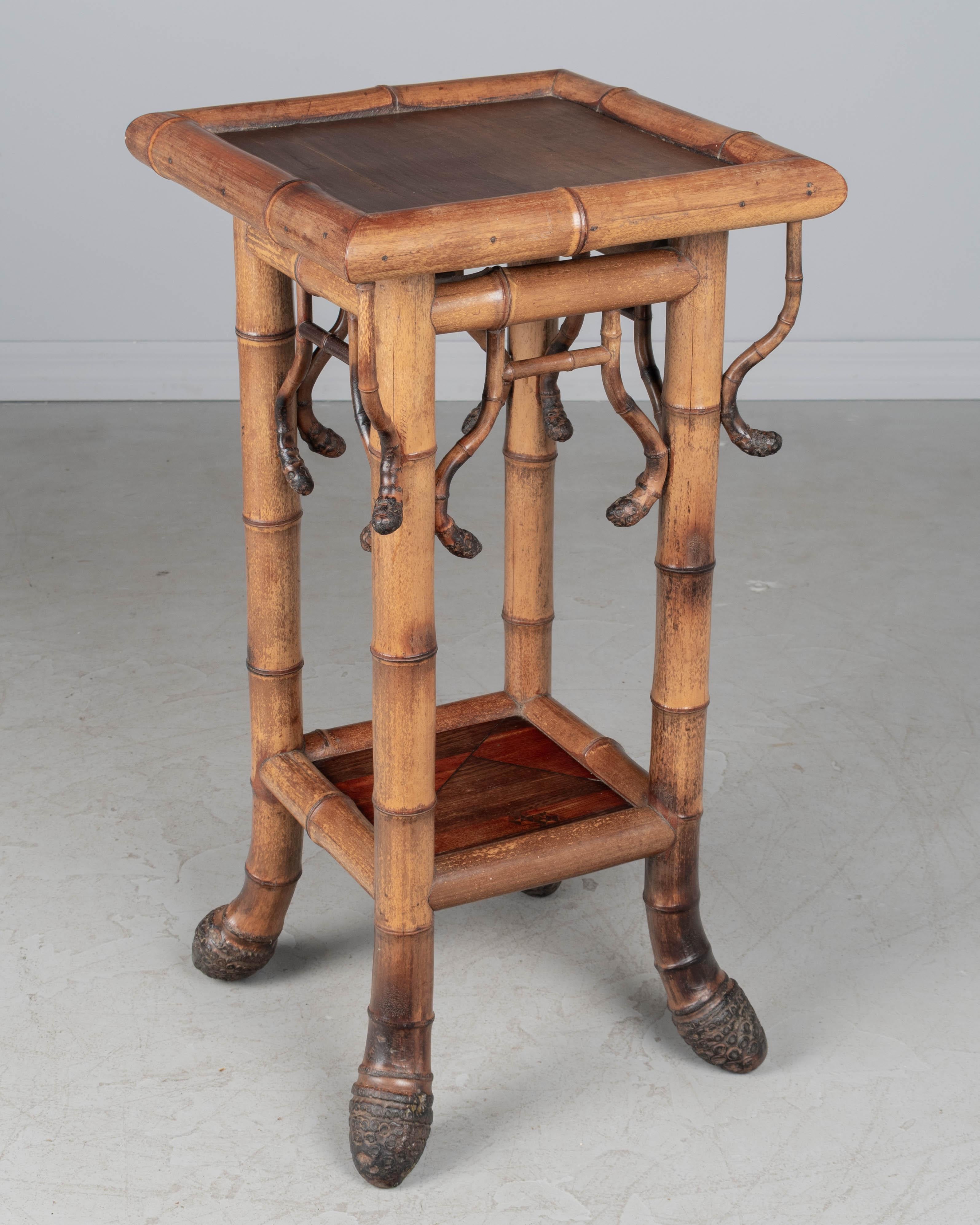 A French Japonisme style plant stand, or side table, with sturdy bamboo frame and slightly curved root end feet and decorative bamboo shoot trim around top perimeter. Bottom shelf made of rosewood marquetry created using a traditional Japanese wood