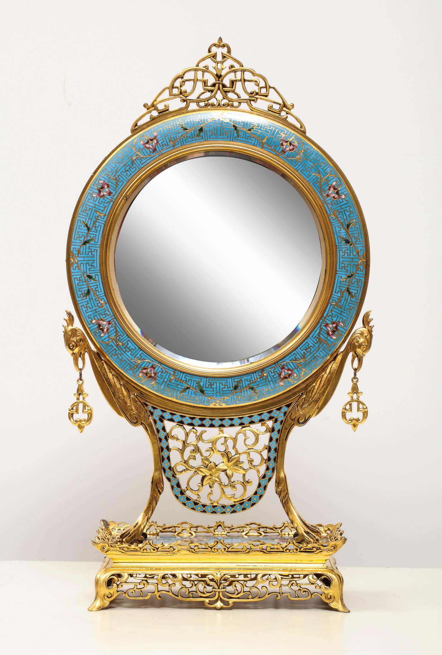 A French Japonisme Ormolu / Bronze and Champleve Cloisonne Enamel Vanity Mirror

attributed to Edouard Lievre, circa 1880

The circular bevelled mirror supported by a pair of birds, on a pierced rectangular base.

Very high