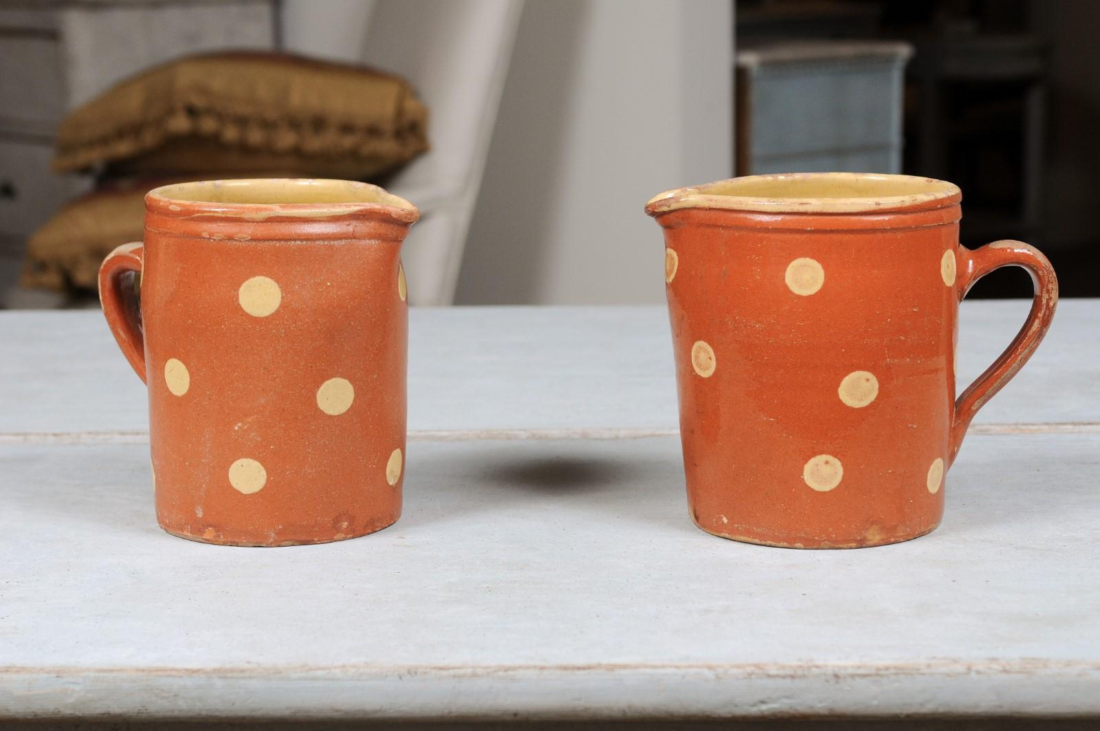 French jaspé ware pottery pitchers from the 19th century, with burnt orange glaze and cream polka dots décor, priced each. These French jaspé pitchers attract our attention with their burnt orange glaze, simply adorned with cream polka dots.
