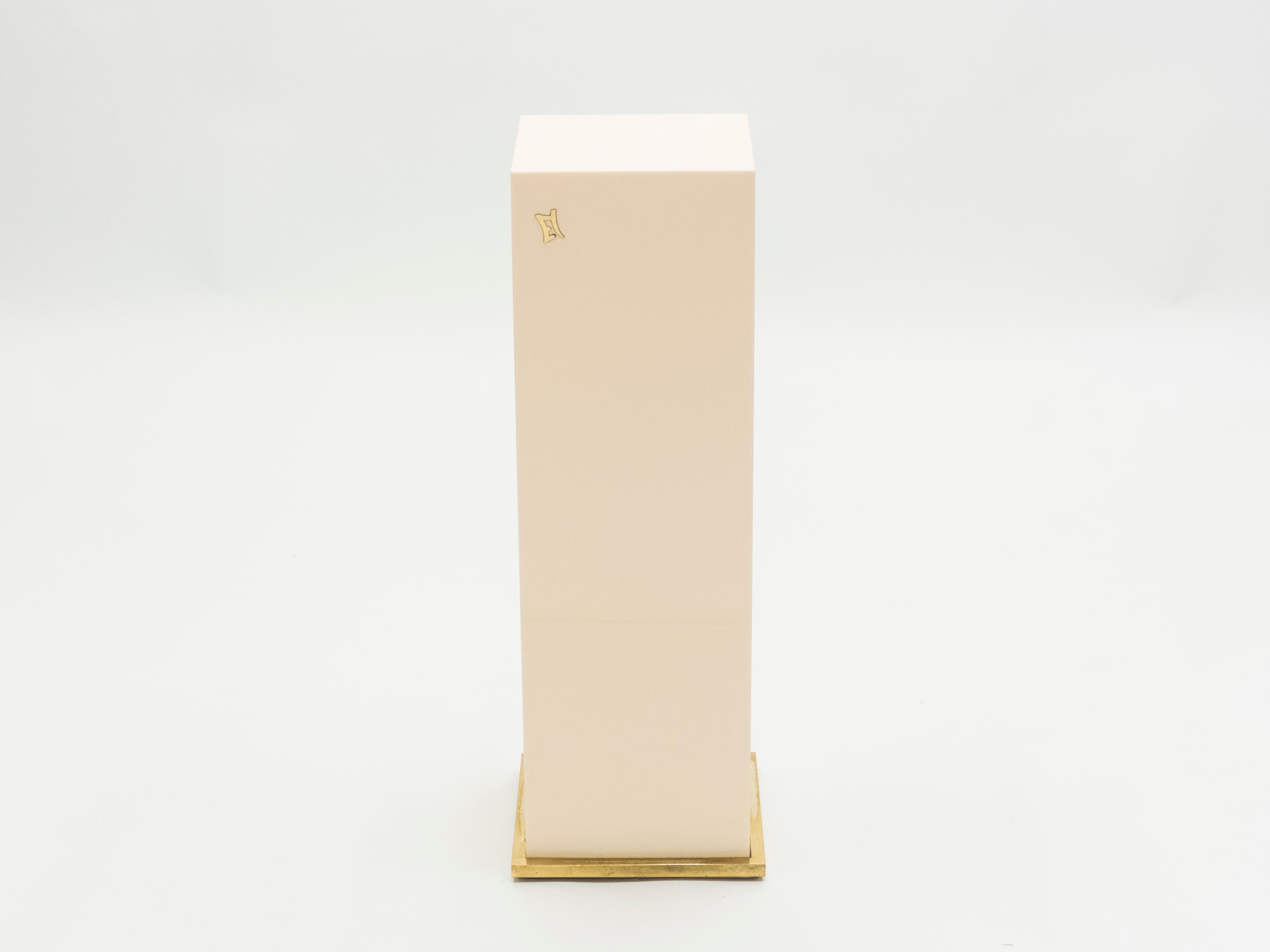 Minimalist and chic, this cubic pedestal tables are both unusual and sleek, serving as understated and anchoring pieces for your living room. The surface is a creamy white lacquer, which rests on a brass base: a color scheme that feels inherently