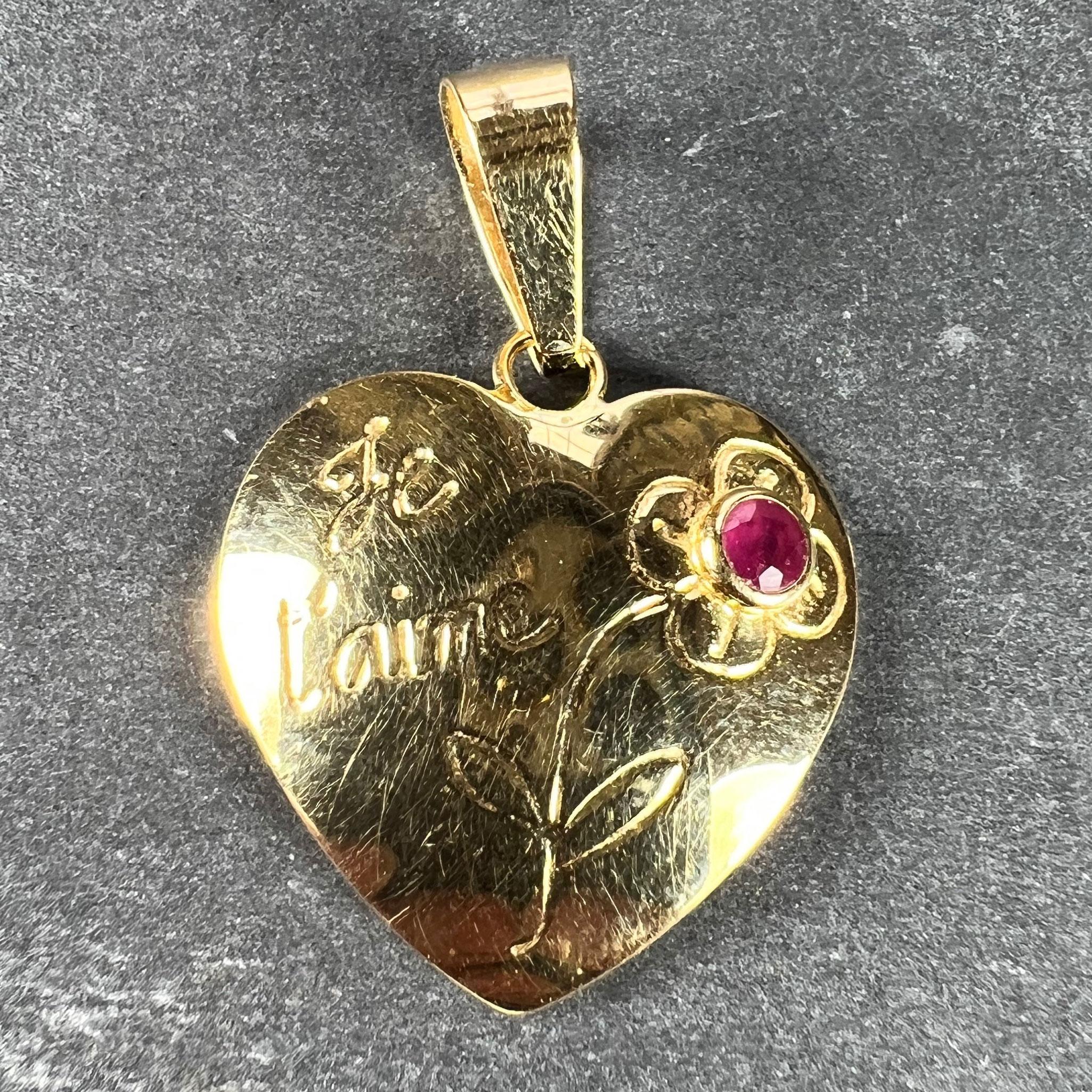 A French 18 karat (18K) yellow gold love letter charm pendant designed as a convex heart with an engraved flower set with a natural untreated ruby weighing approximately 0.10 carats and the words 'Je t'aime' in cursive to one side. 

Stamped with an