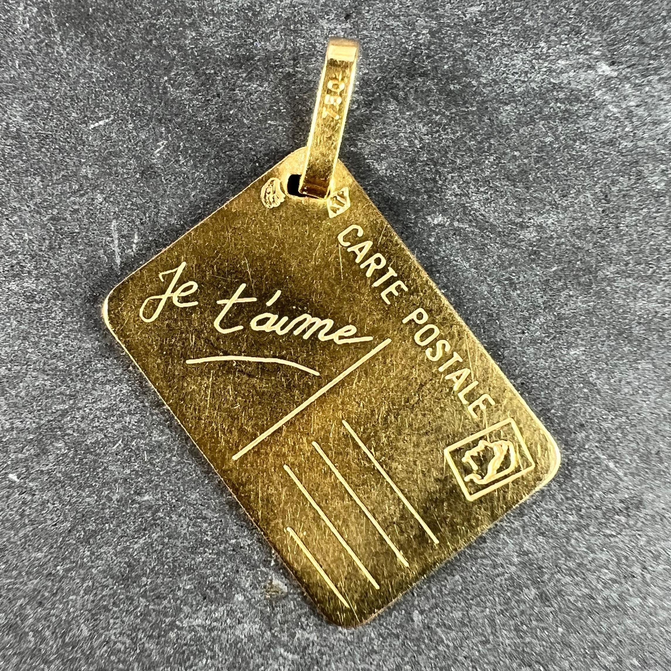 A French 18 karat (18K) yellow gold love letter charm pendant designed as a postcard with blank address field, stamp and the words 'Je t'aime' in cursive to one field. Engraved 'Maman' (Mother) to the reverse.

Stamped with the eagle's head for
