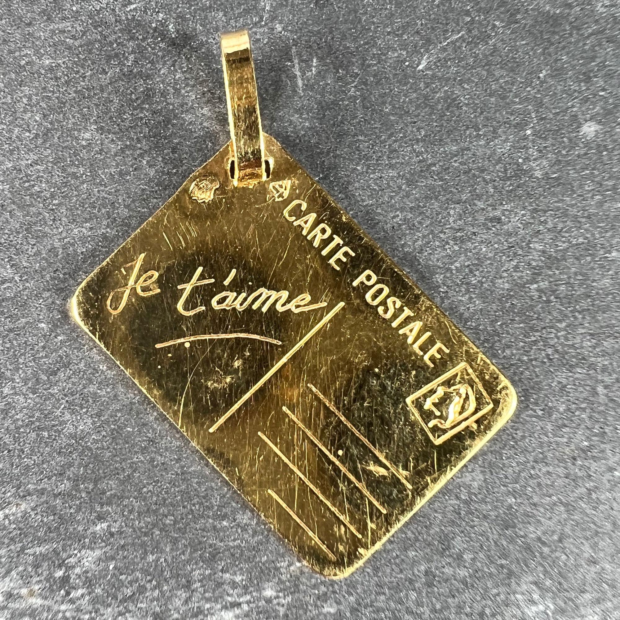 A French 18 karat (18K) yellow gold love letter charm pendant designed as a postcard with blank address field, stamp and the words 'Je t'aime' in cursive to one field.

Stamped with the eagle's head for French manufacture and 18 karat gold and an