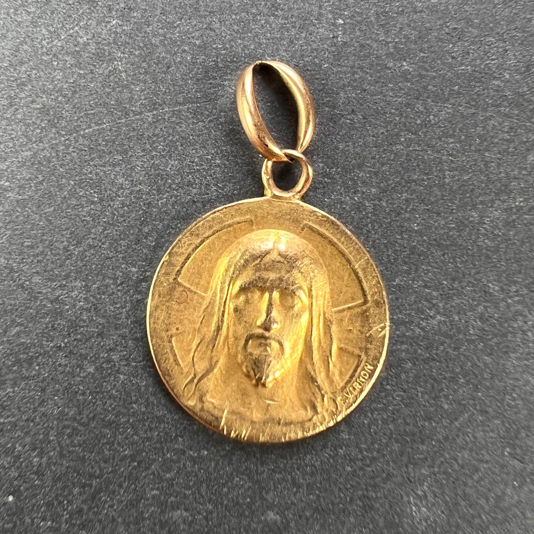 An 18 karat (18K) yellow gold charm pendant depicting the face of Jesus Christ with a cross. Engraved to the reverse with the date 22 Novembre 1937-1952. Signed F. Vernon and stamped with the eagle mark for 18 karat gold and French manufacture.
