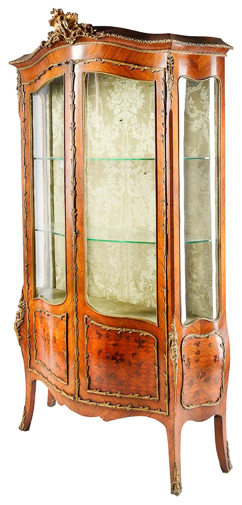 A good quality late 19th century French Louis XVI style Kingwood vitrine, having gilded ormolu mounts, serpentine fronted with shaped glass panels, glass shelves within, foliate marquetry inlay to the door panels and raised on elegant out swept legs.