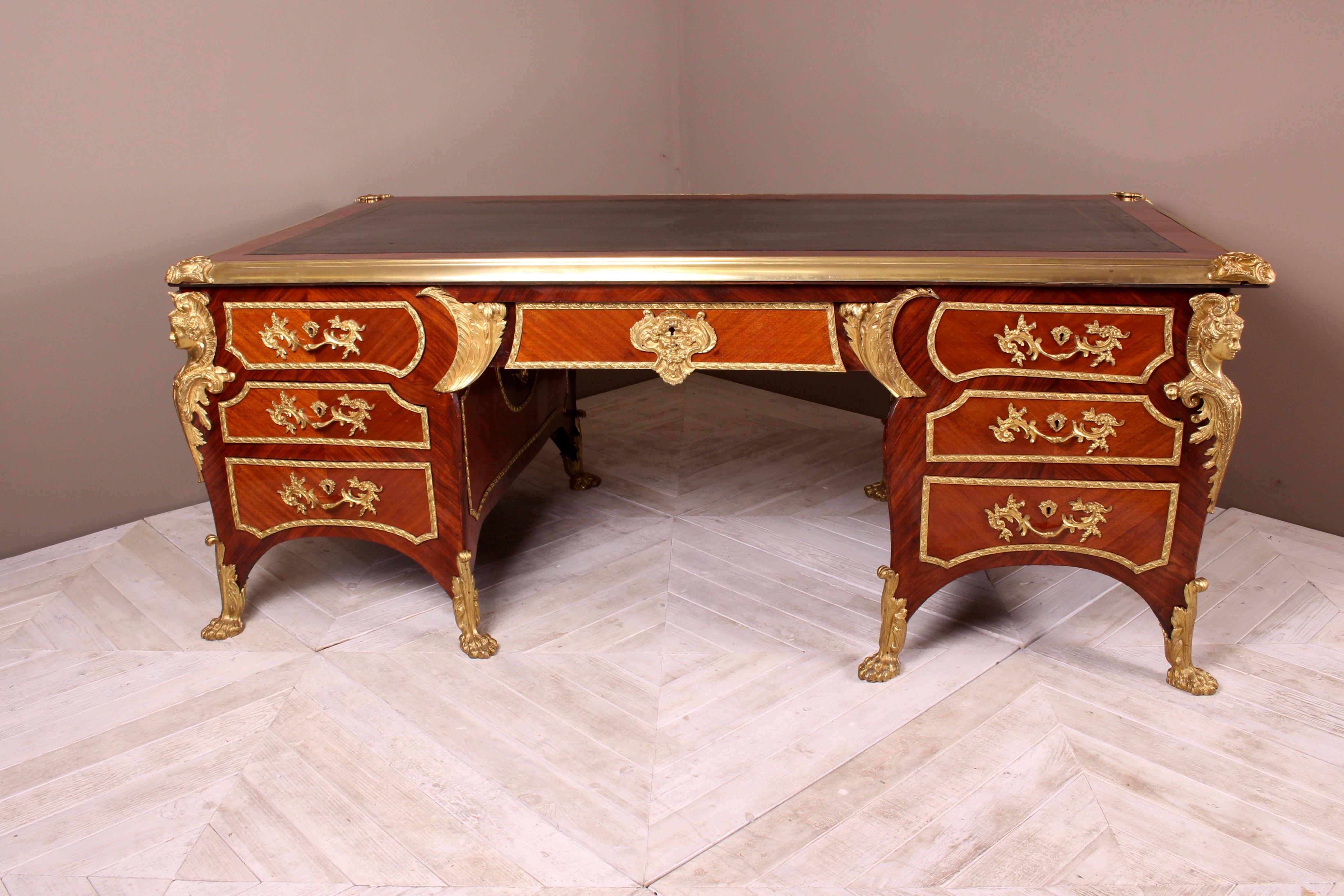A fine French kingwood and ormolu-mounted bureau plat by the renowned and luxury Parisian furnishers, Au Gros Chene, Paris. Having gilt-tooled leather top framed with timber crossbanding and gilt bronze mounts to each corner. Below is a large