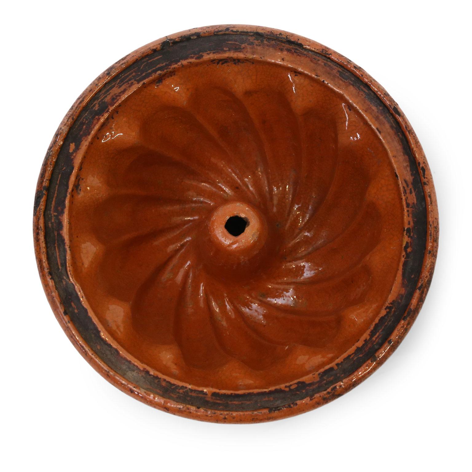 French Kouglof mold, in a ruddy-terracotta color glaze, from Alsace. Glazed refractory earthenware bunt cake mold dating to the late 18th or early 19th century.