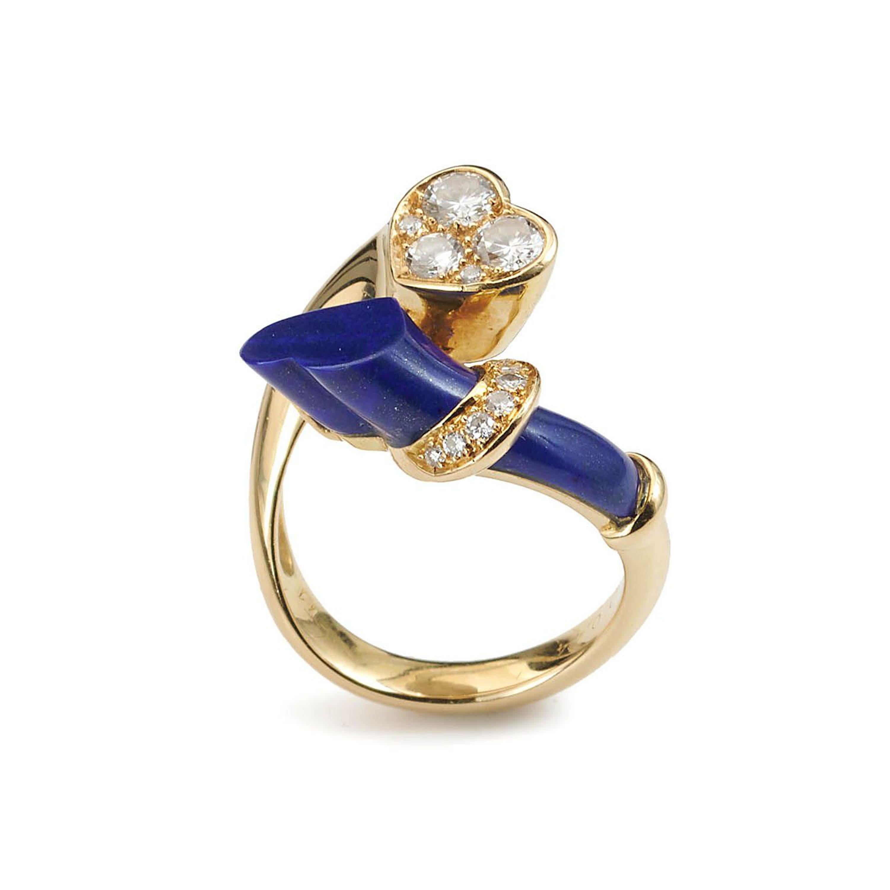 A vintage, French, lapis lazuli, diamond and gold, hearts entwined crossover ring, with the terminal of one heart, pavé set with five round brilliant-cut diamonds, in varying sizes, the other terminal with a bar of lapis lazuli, faced with a heart,