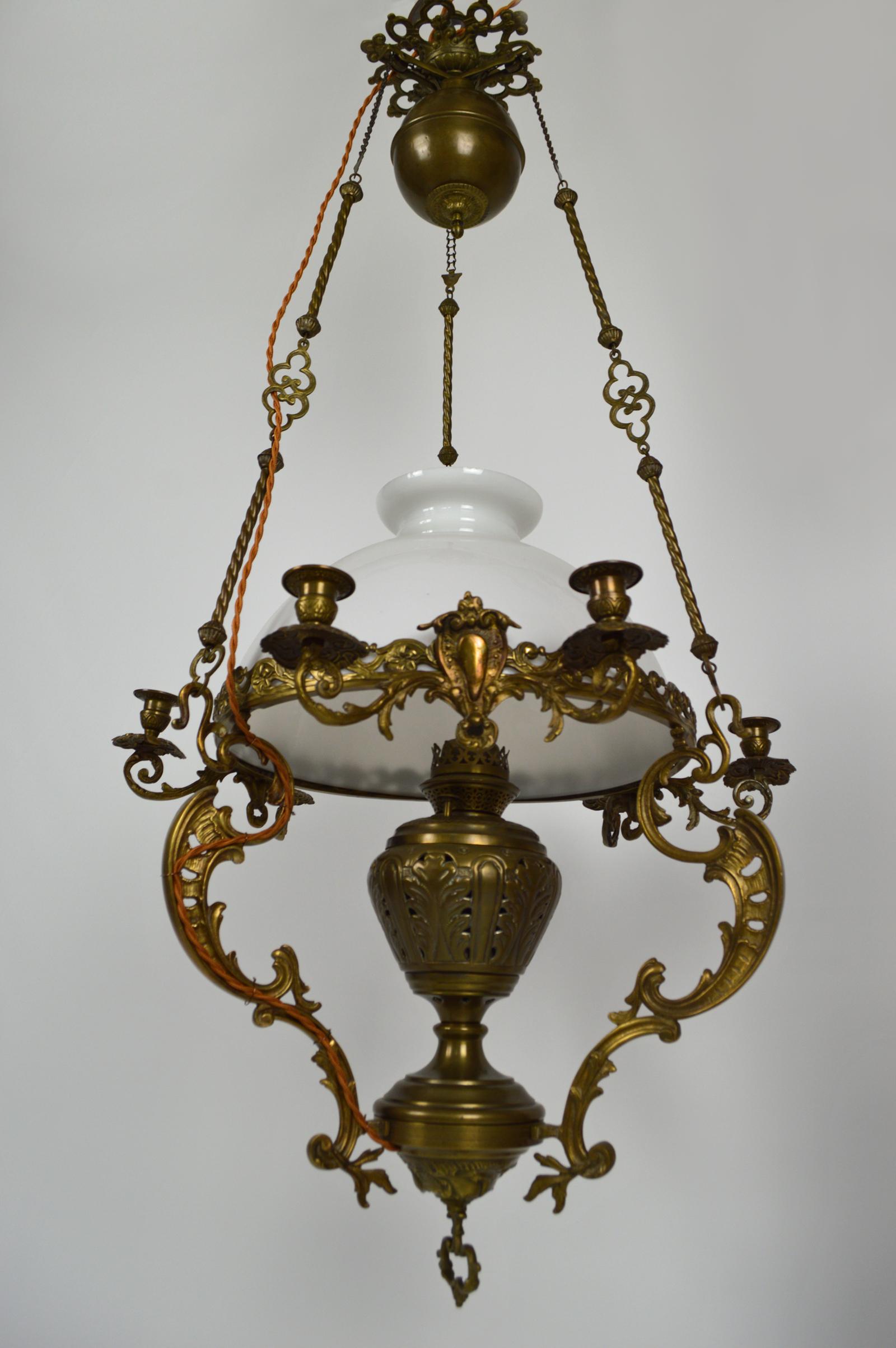This large chandelier with drop-down suspension in bronze and brass was produced in the late 19th century. It features elements of Rococo / Regency / Louis XV (candlesticks) and influences or Japanese / floral Art Nouveau (support of the opaline