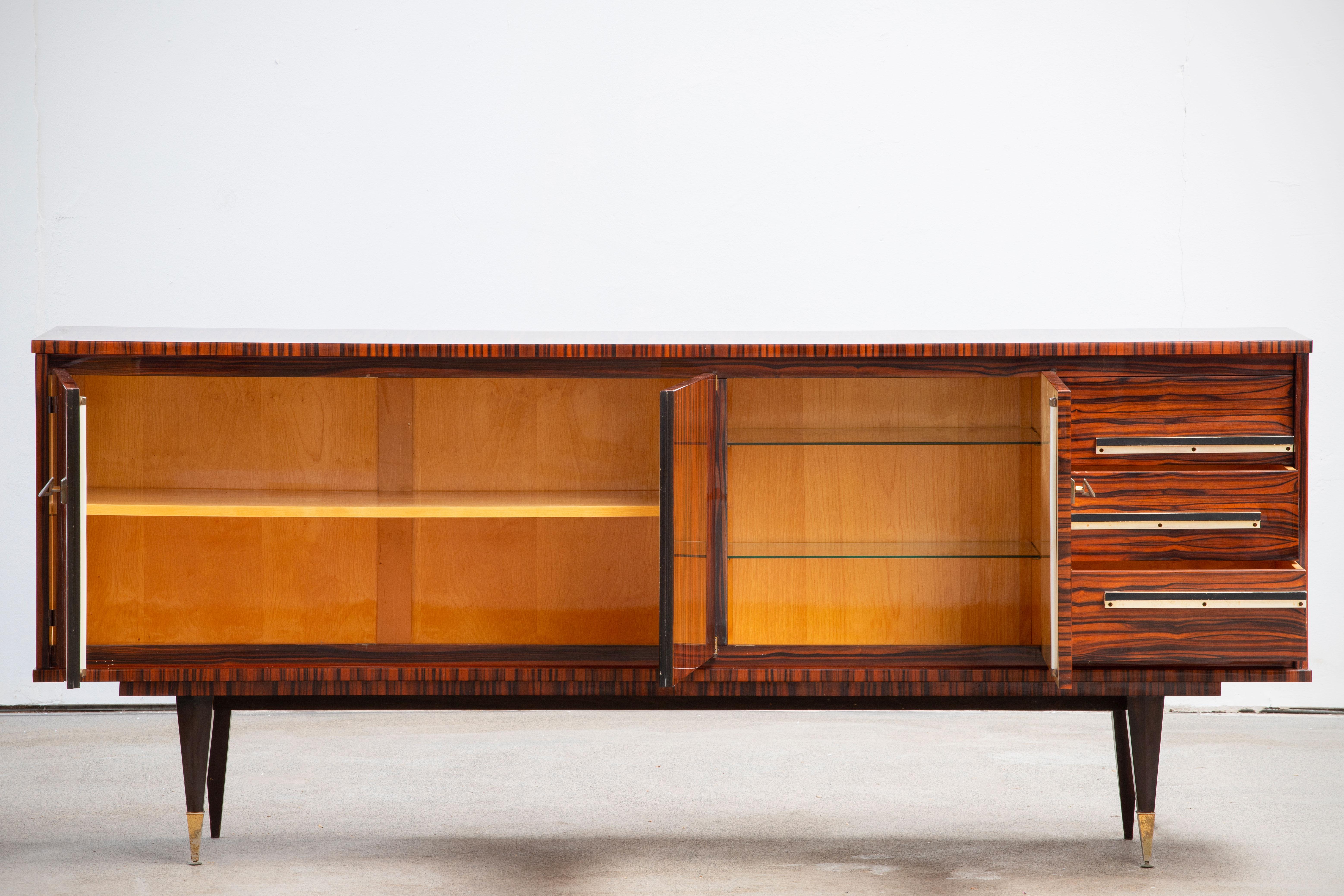 French Art Deco sideboard, credenza, with bar cabinet. The sideboard features stunning Macassar ebony wood grain. It offers ample storage, with shelve behind two doors on the left and three drawers and additional door on the right. Both sides of the