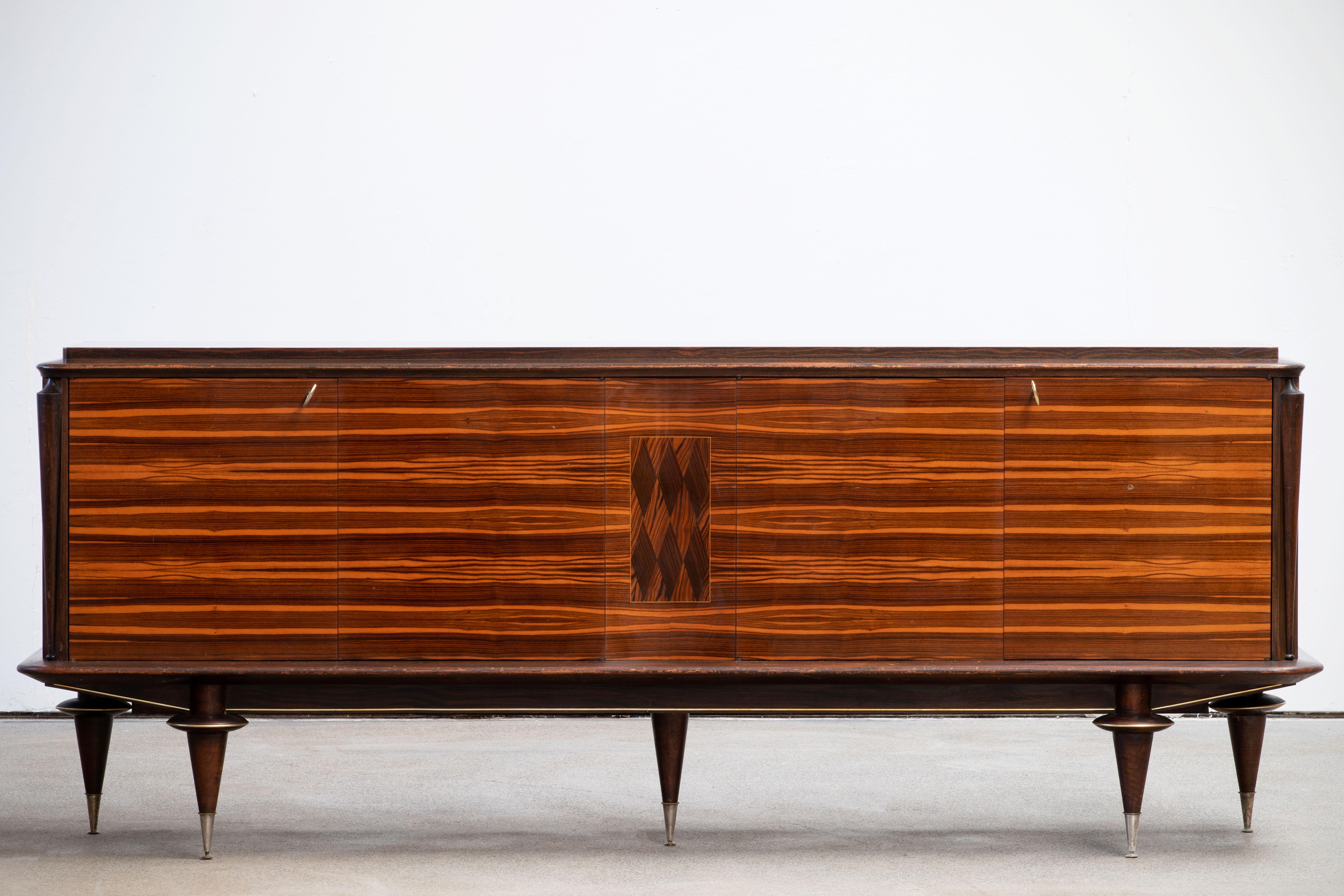French Art Deco sideboard, credenza. The sideboard features stunning Macassar wood grain with a geometric pattern in the center. It offers ample storage, with shelve behind the doors. Both sides of the cabinet lock, and two original keys are