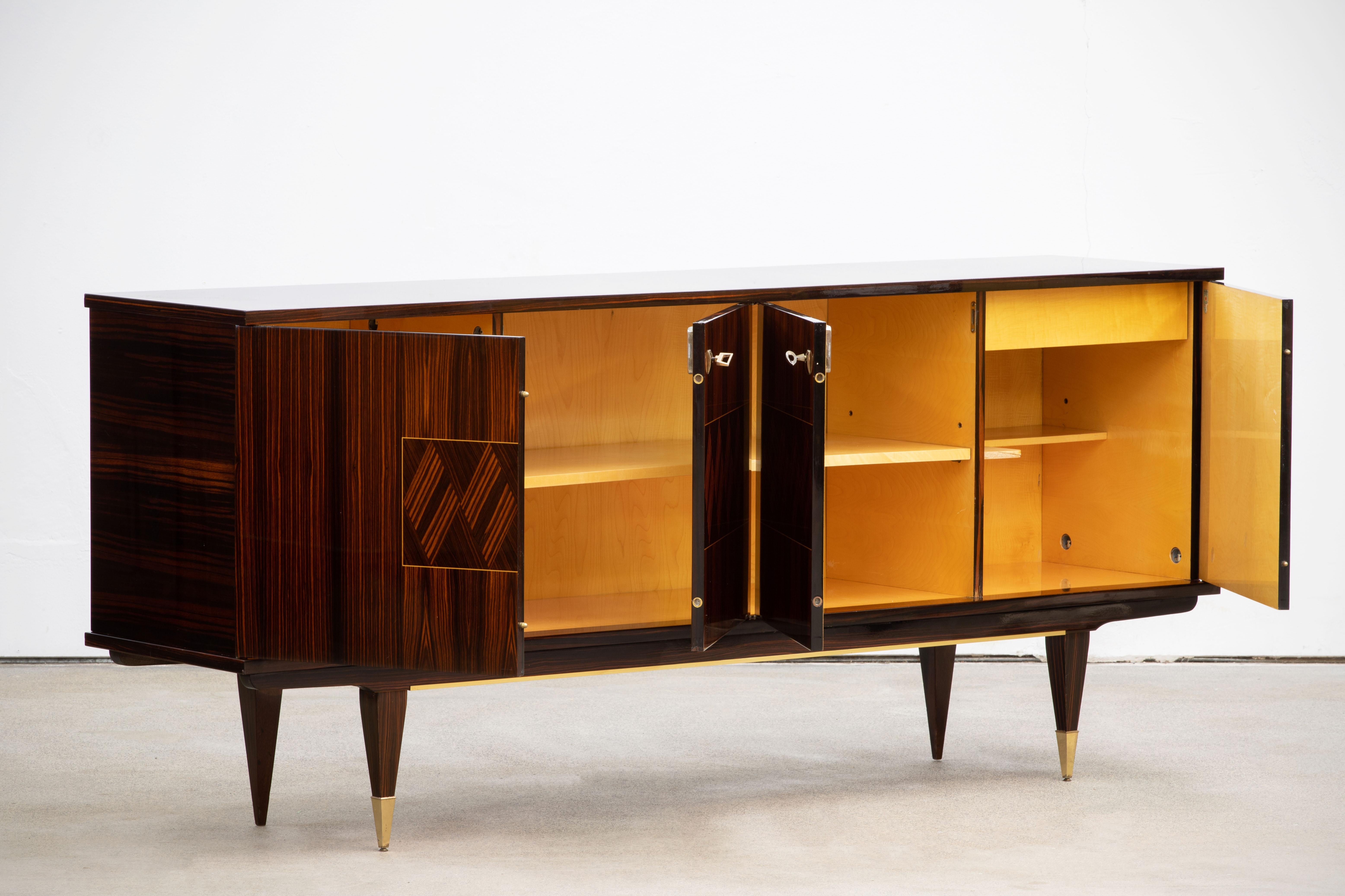 French Art Deco sideboard, credenza. The sideboard features stunning Macassar wood grain with a geometric pattern in the center. It offers ample storage, with shelve behind the doors. Both sides of the cabinet lock, and two keys are included. The