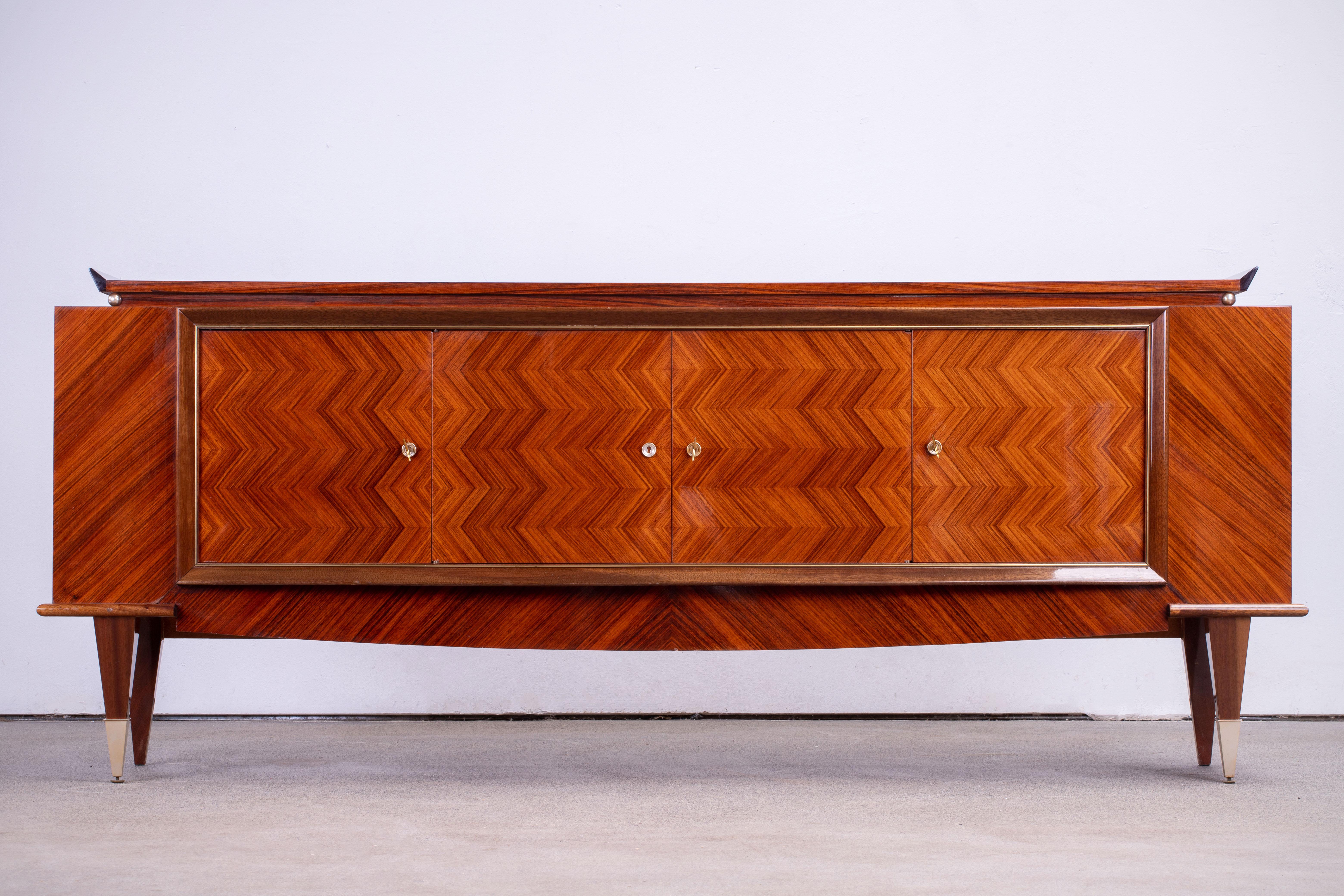 French Art Deco sideboard, credenza, with bar cabinet. The sideboard features stunning Macassar ebony wood grain. It offers ample storage, with shelve behind two double doors with a colonne of drawers on the right. 
Both sides of the cabinet lock,